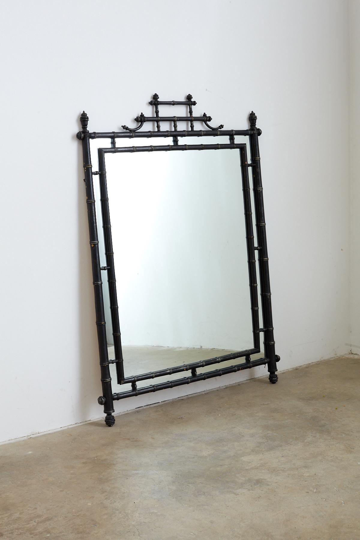 Impressive faux bamboo mirror with a black lacquer finish made in the English chinoiserie taste. Features a beautiful turned bamboo frame made by carver's guild. The lacquer finish has a stylish satin look with silver accents.