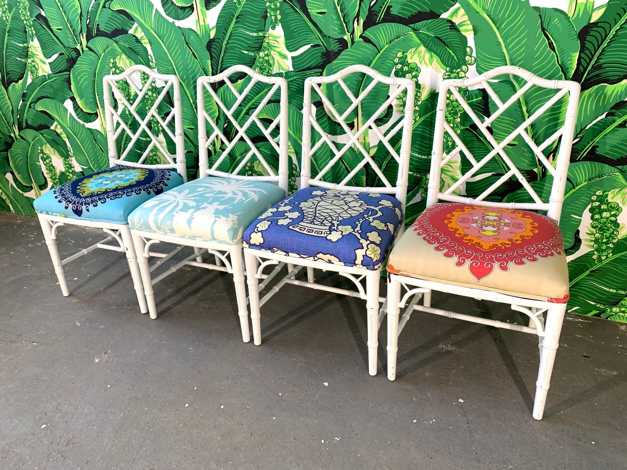 Set of four faux bamboo dining chairs in Chinese Chippendale style. Perfect touch of chinoiserie in any decor. Cheery upholstery unique to each chair. Very good vintage condition with only minor abrasions consistent with age.