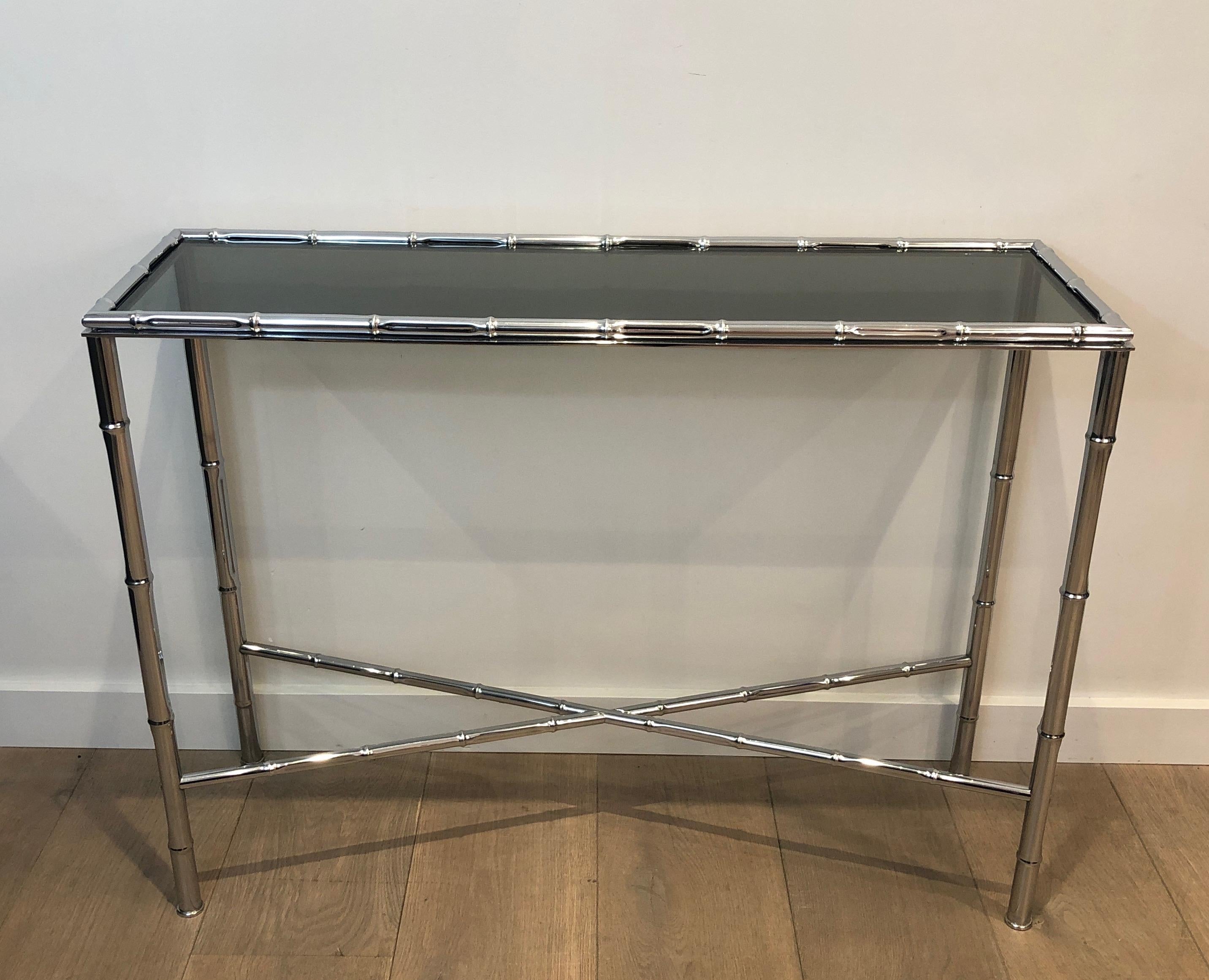 This faux-bamboo console and its matching mirror are made of chrome. This is a French work, in the style of Maison Baguès, circa 1970.