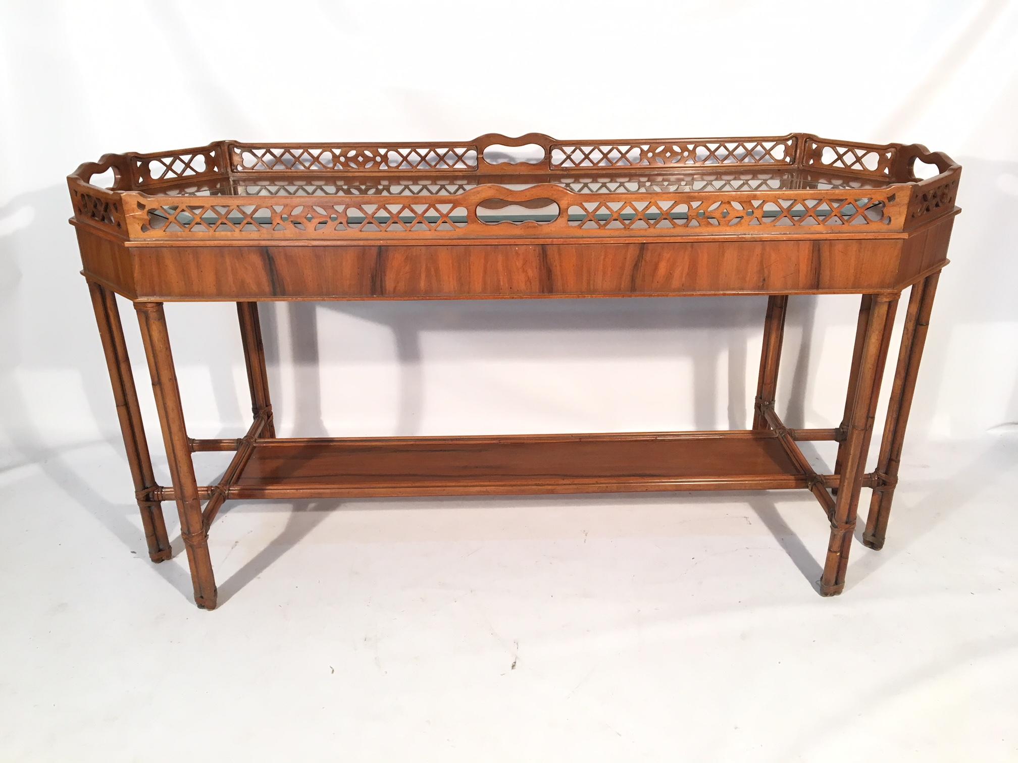 Faux bamboo console table features beveled glass top insert and carved wood gate details. Very good condition with very minor signs of age appropriate use.