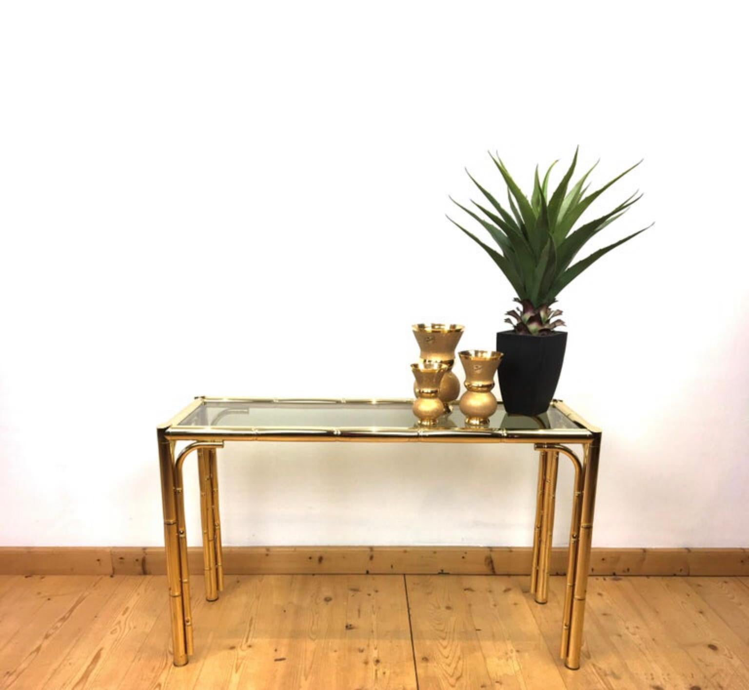 Faux bamboo console table. 
This metal faux bamboo console table dates from the 1970s and was Made in Italy. 
It's an elegant and stylish wall table with a smoked glass top. 

Italian design console table from the late 20th Century. 
It fits many