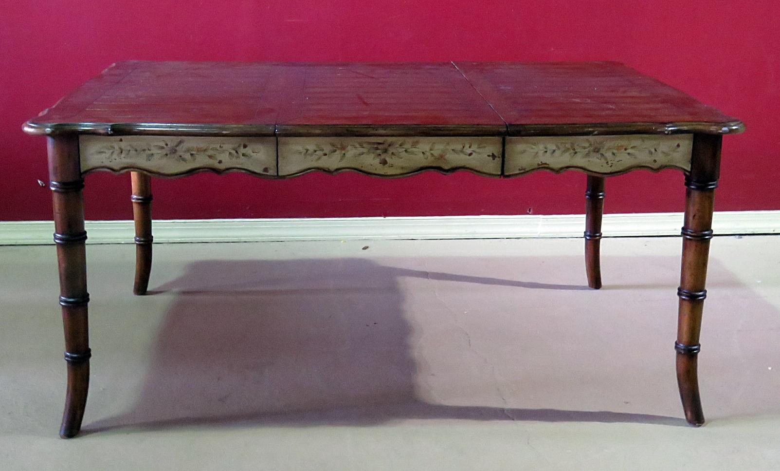 This is a unique and fanciful French Faux bamboo distressed painted dining room table with two silverware drawers and one 20 inch leaf. The table has been designed to look antique and has a high quality painted finish and strong sturdy construction.