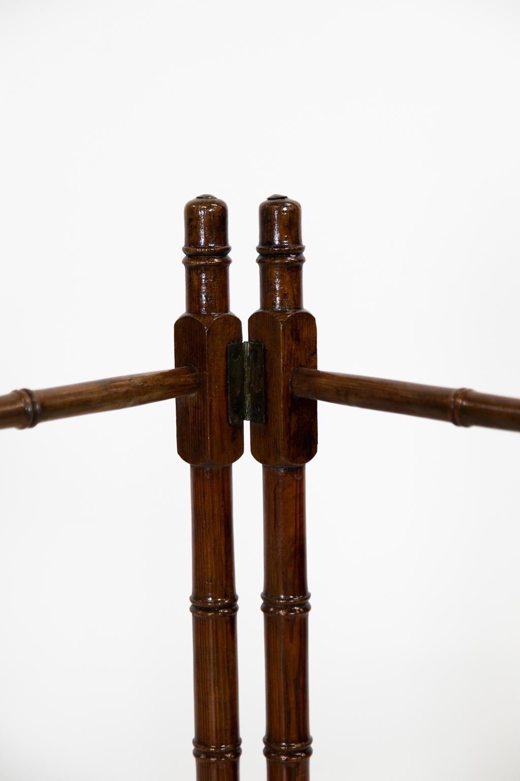 This faux bamboo towel rack has three hanging bars on each section, wooden finials on all four legs, and a metal button on each top.
  