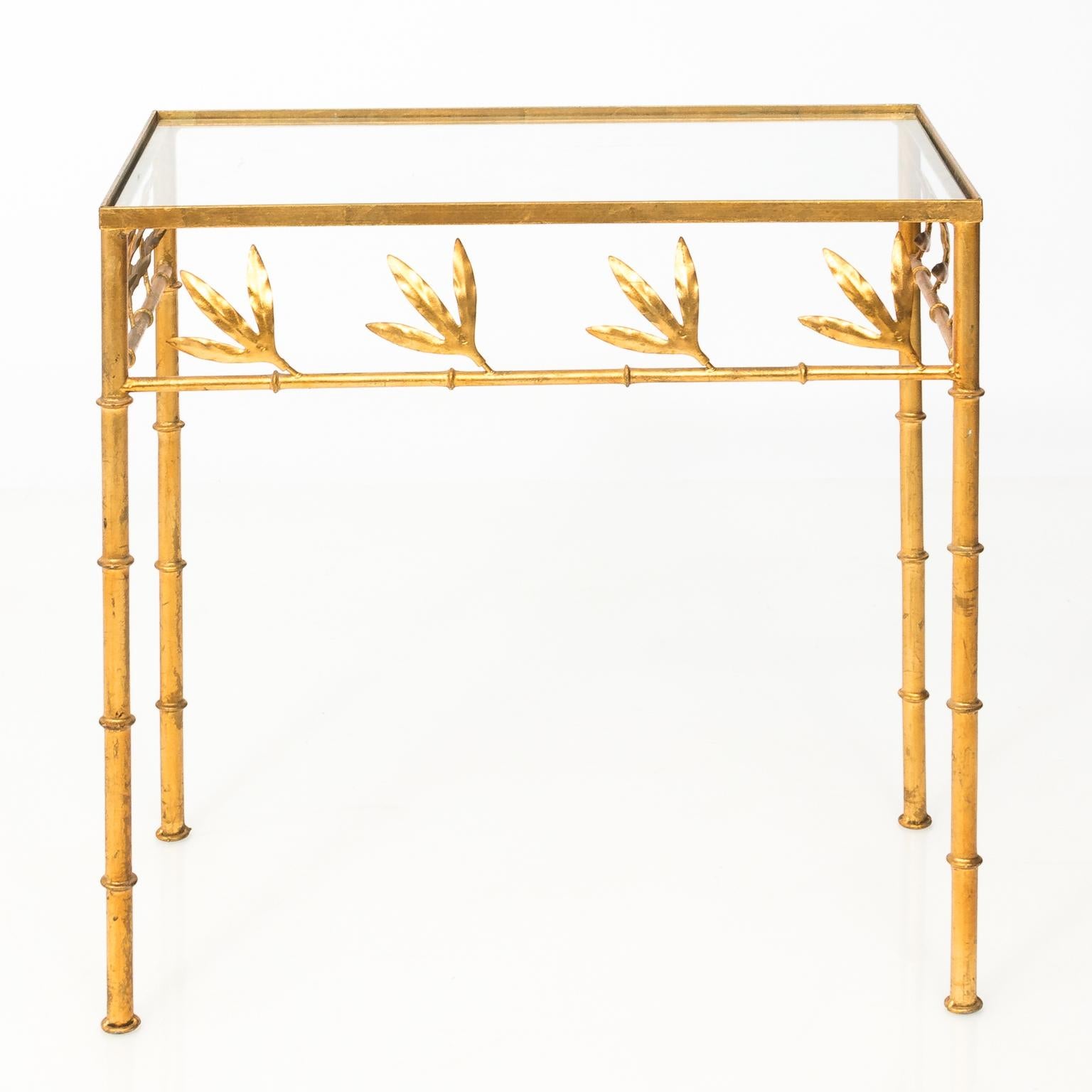Set of two glass top nesting tables with gilt metal faux bamboo bases, circa 1960-1980. Please note of the small crack in corner of glass on the smallest table.
 