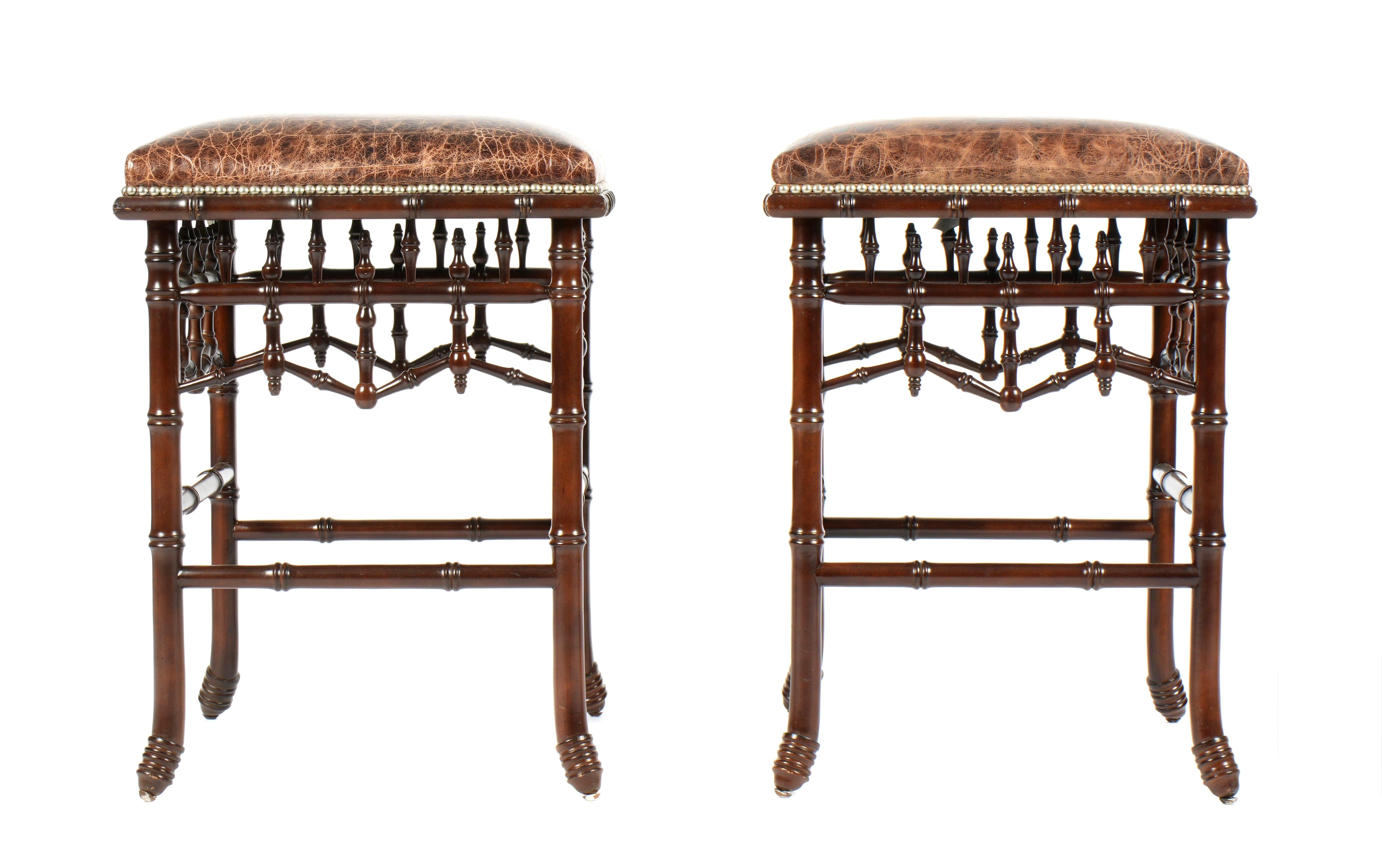 Set di quattro sgabelli con una raffinata struttura in finto bambù e un'intricata lavorazione del legno. I sedili sono rivestiti in una ricca ecopelle con motivo a coccodrillo e rifiniti con le classiche decorazioni a testa di chiodo per una