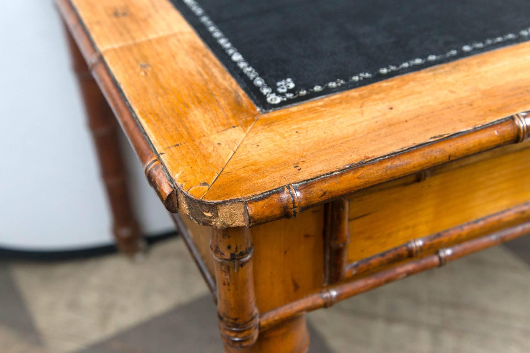 Dating from the Edwardian period, this faux bamboo writing table has two drawers and a silver tooled leather top.
The legs and the edging are faux bamboo turned. There porcelain casters appear to be original. The height from floor to under the
