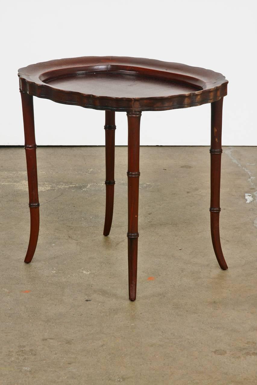 Diminutive mahogany tray table or drink table featuring faux bamboo carved legs. Oval form with a scalloped edge and a galleried top. This tray could also be used to support a larger tray. Constructed with mortise and Tenon style joinery and a rich