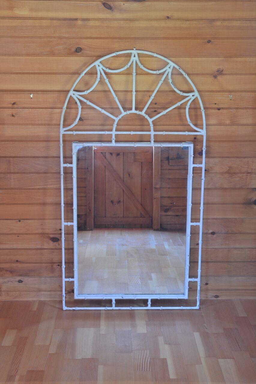 A white painted faux bamboo mirror with metal surround, American, circa 1970, 56 ins high by 30 ins wide.