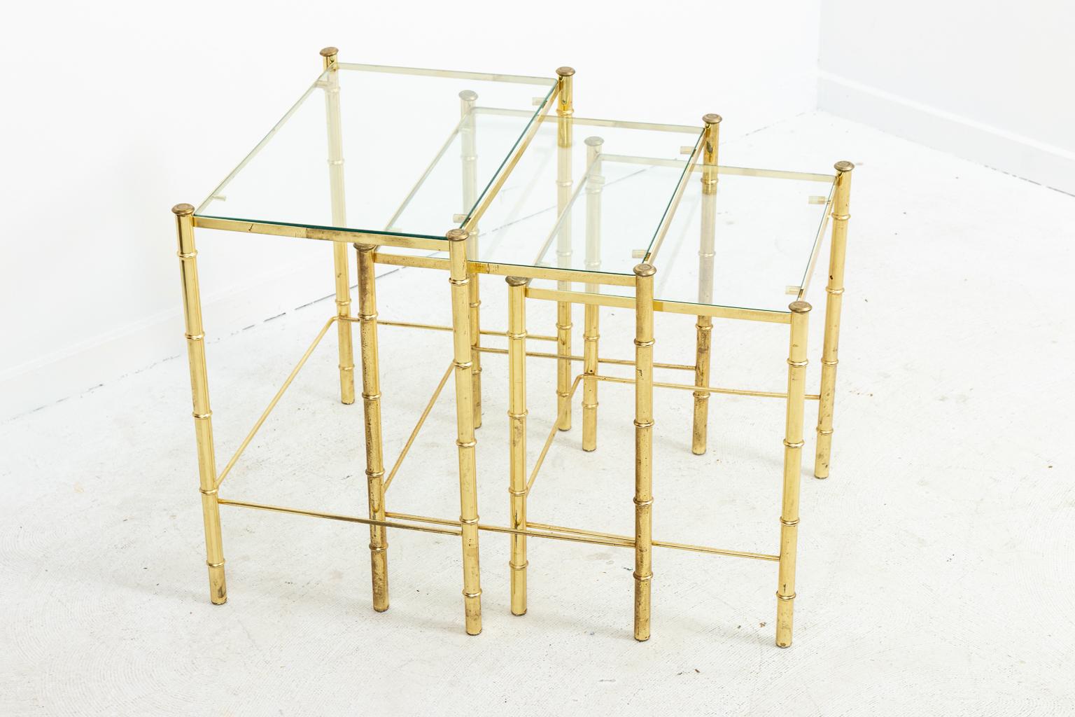 Faux bamboo frame nesting tables with glass tops, circa 1970s. Please note of wear consistent with age.