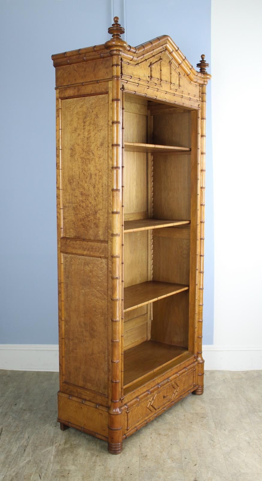 A large and imposing honey colored faux bamboo bookcase from France. The piece boasts four roomy shelves, fully adjustable (we are only showing three here but there is a fourth) with a wide bottom drawer. The cornice and lower drawer feature