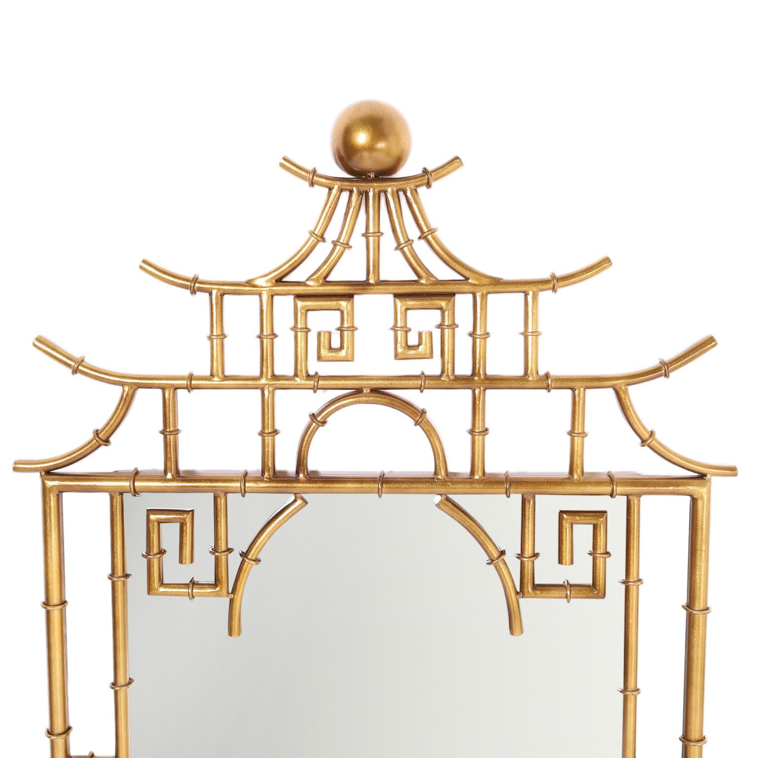 Wall mirror crafted in metal with a gilt finish in an Asian modern form with a pagoda style top and Chinese Chippendale lines.