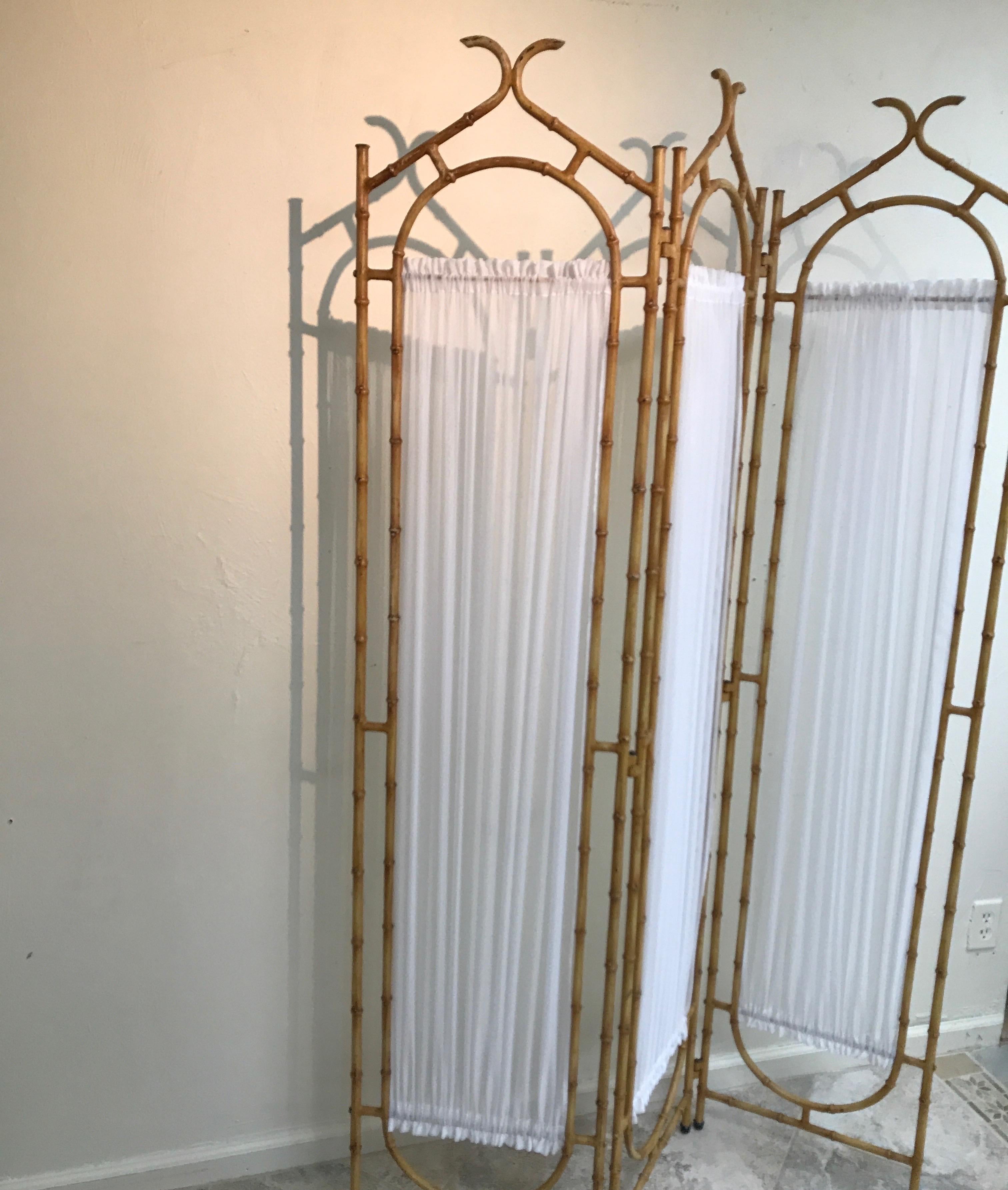 Faux bamboo painted metal pagoda style three-panel screen with white sheer fabric.