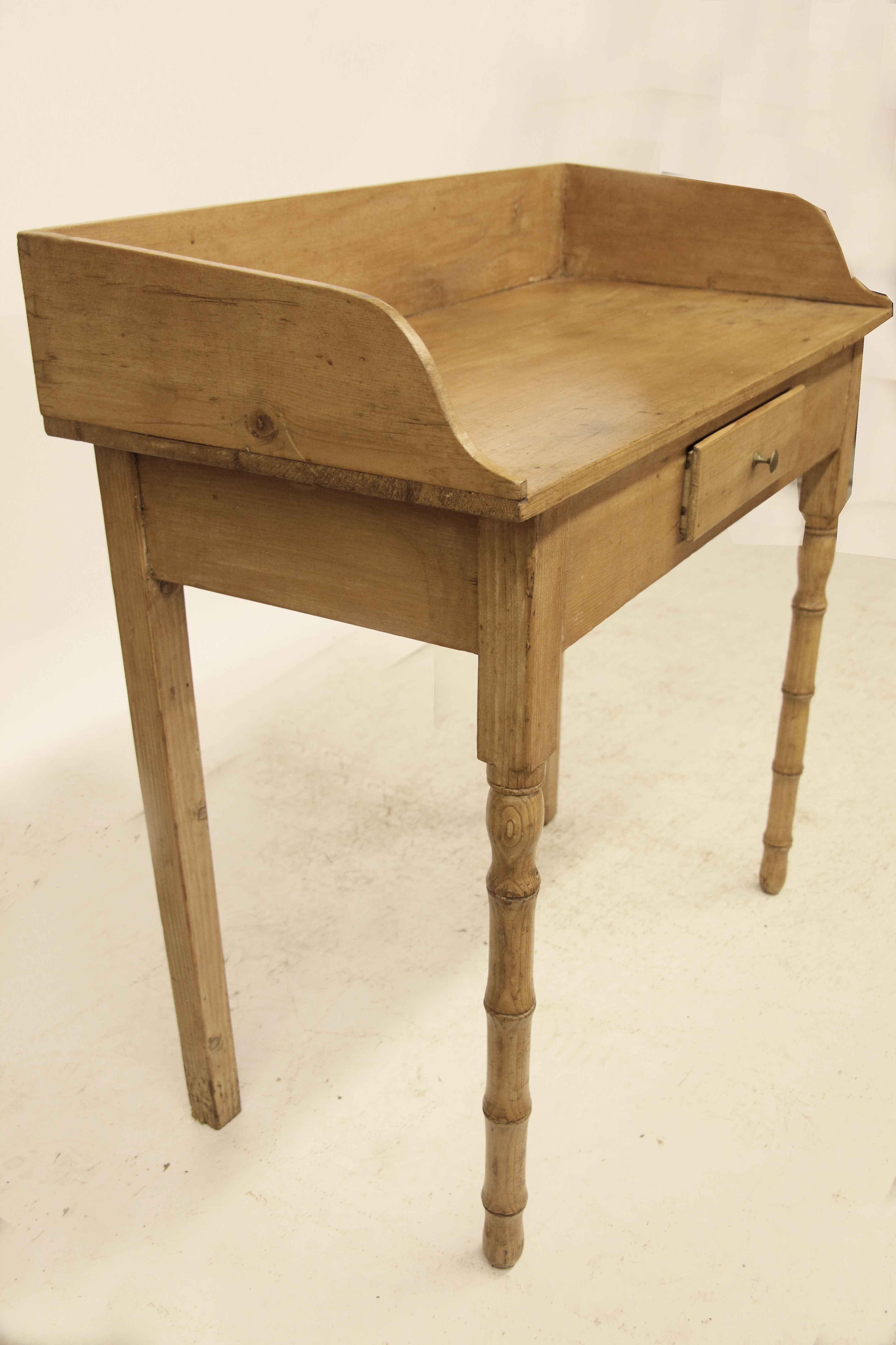 Faux bamboo pine one drawer table, the top with gallery surround, front legs with faux bamboo turnings, back legs are square; single drawer with brass knob. Since there is sufficient overhang on the sides and back, if desired, the gallery could be