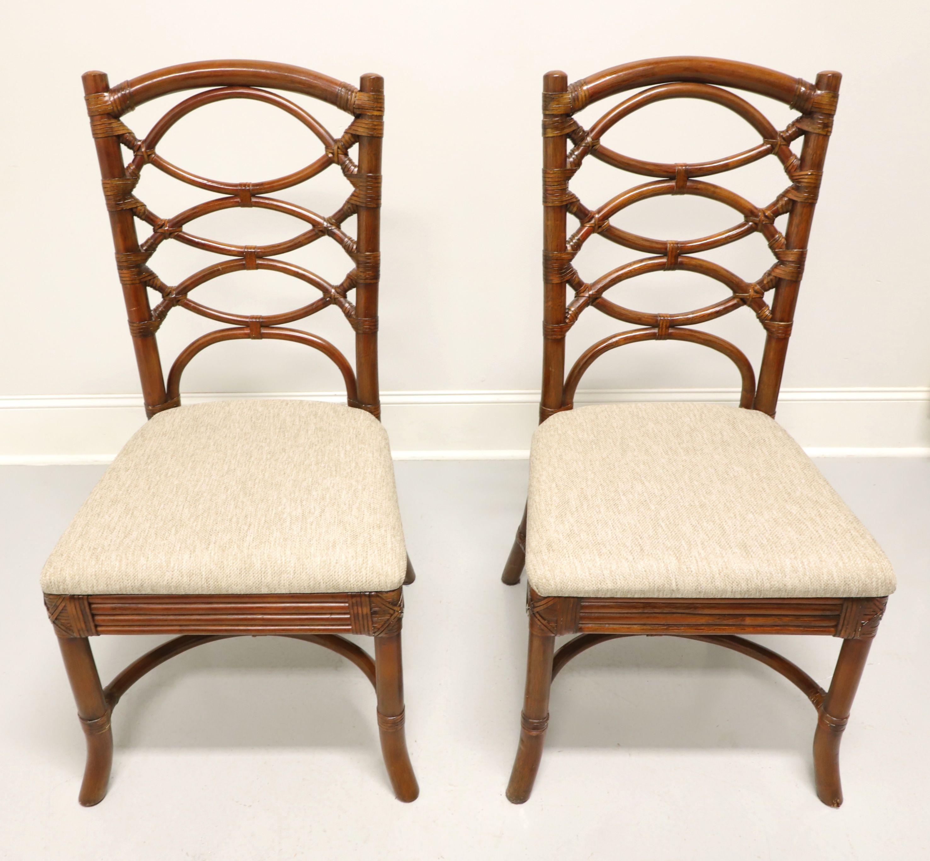 A pair of Asian influenced dining side chairs, unbranded. Faux bamboo with rattan strapping, circular design backrest, neutral color fabric upholstered seat, decorative apron, flared legs and curved stretchers. Likely made in Eastern Asia, in the