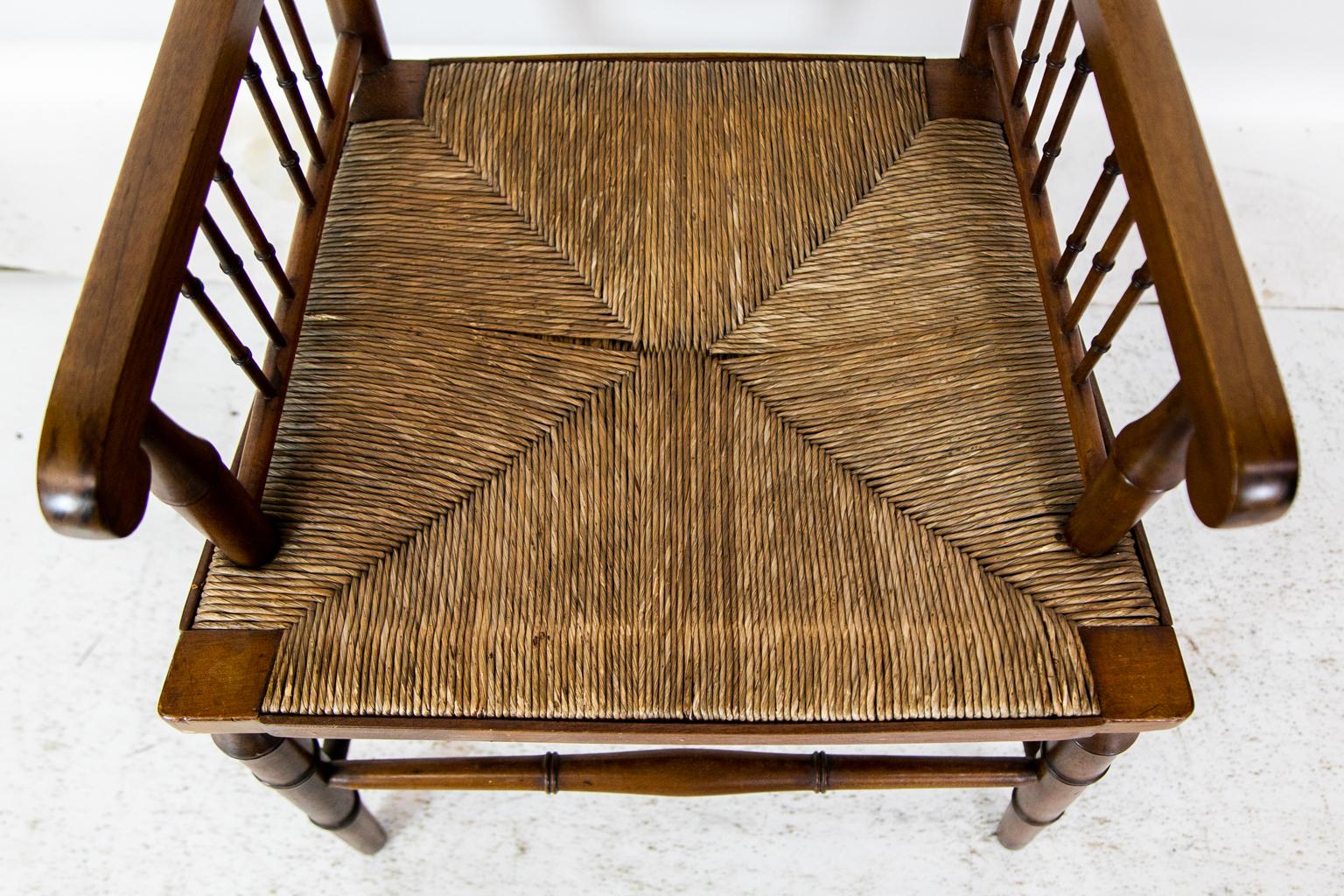 This arm chair has faux bamboo horizontal spindles in the back and arms. It has the original rush set in excellent condition. The front legs and cross stretcher have faux bamboo turnings. There are double turn stretchers connecting the front and