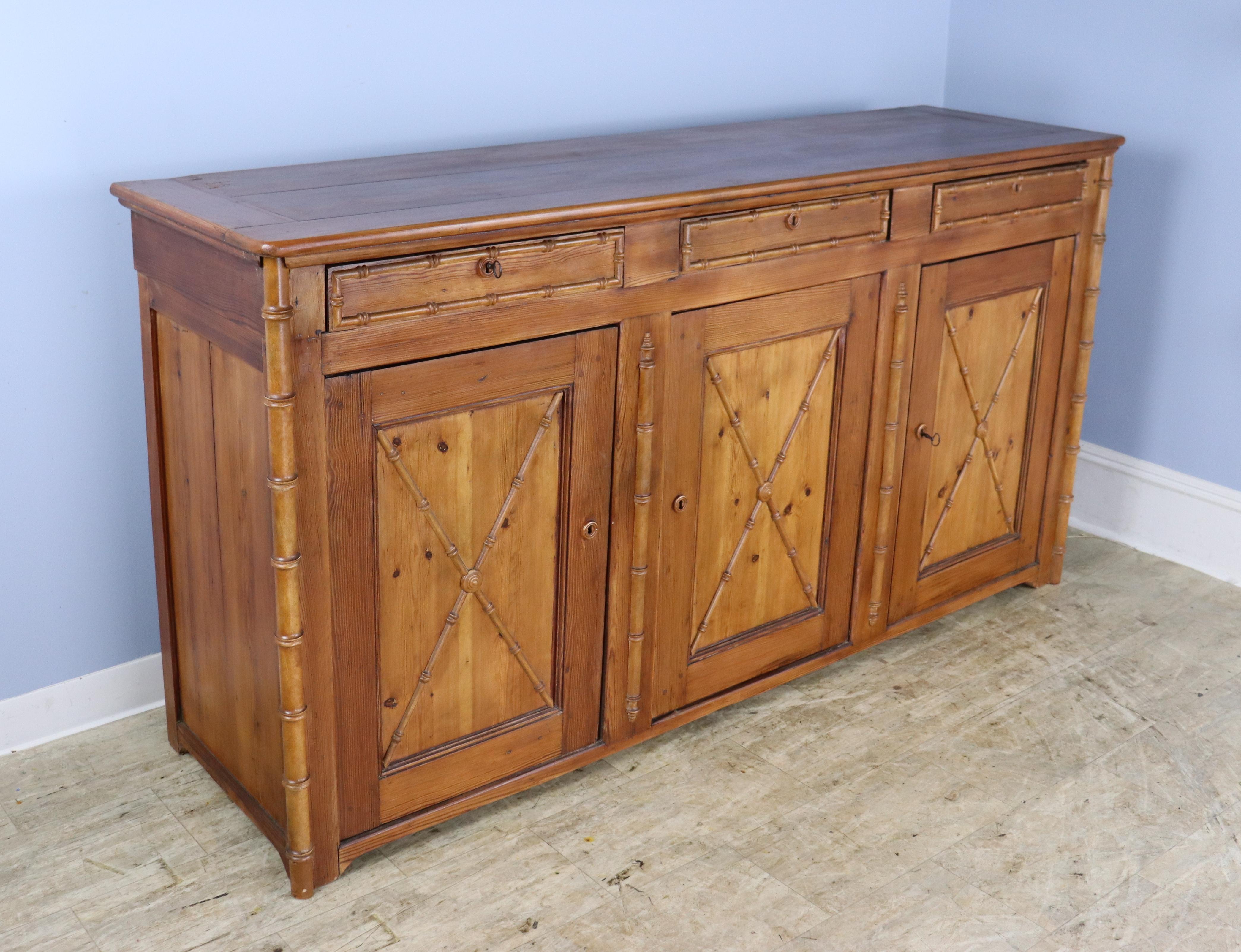 A three door enfilade or buffet with three compartments and a non-adjustable interior shelf.  All three doors lock with the original key.  The bamboo trim and mouldings are charming, and give this piece real visual impact.  There is some light wear