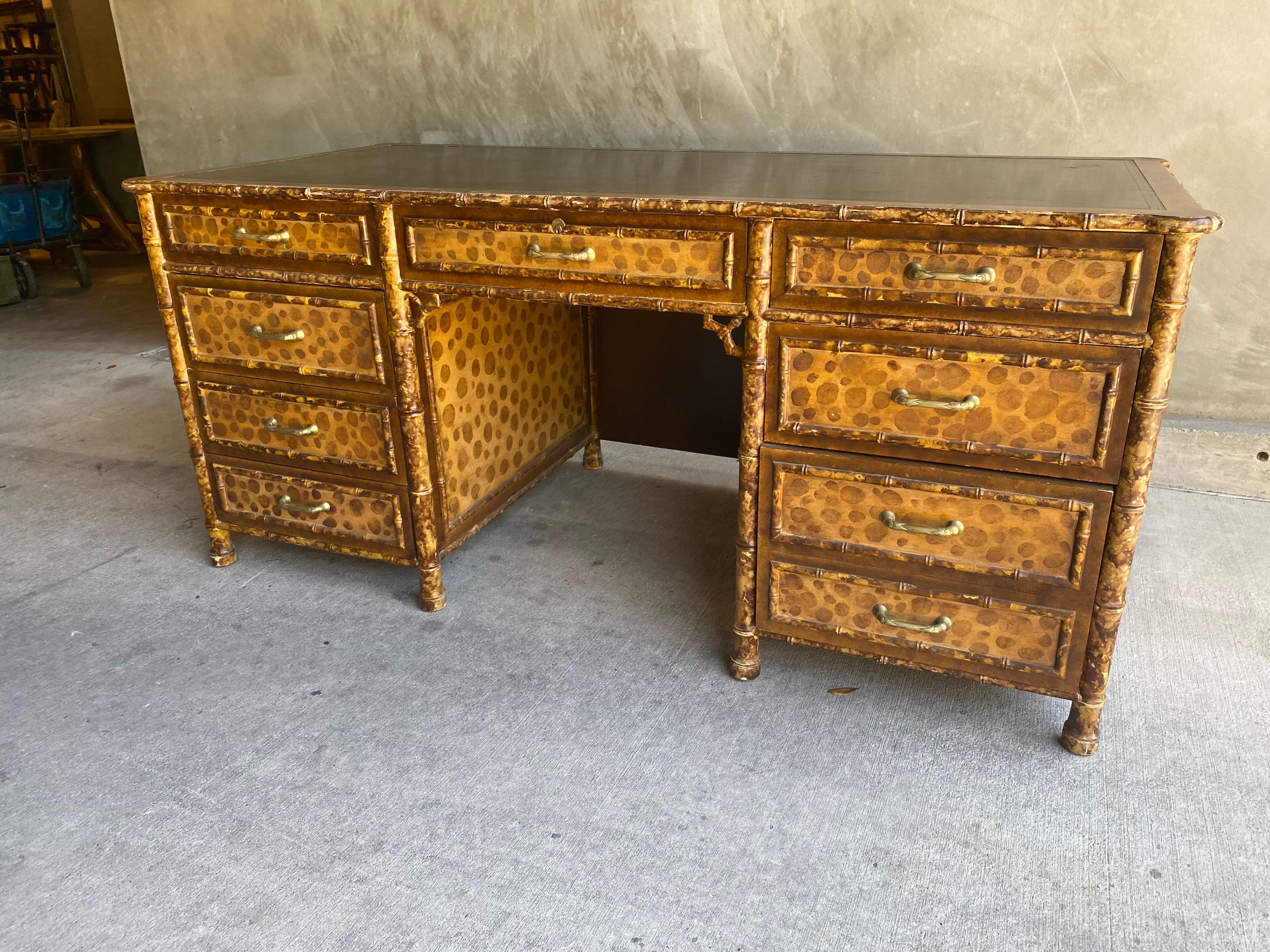 A high style desk, finished on all sides in hand painted faux bamboo and tortoise shell (almost leopard print). Well made piece of furniture, heavy and with nice joinery. Inset leather top is coffee to ebony in color. Side drawers are locking, but