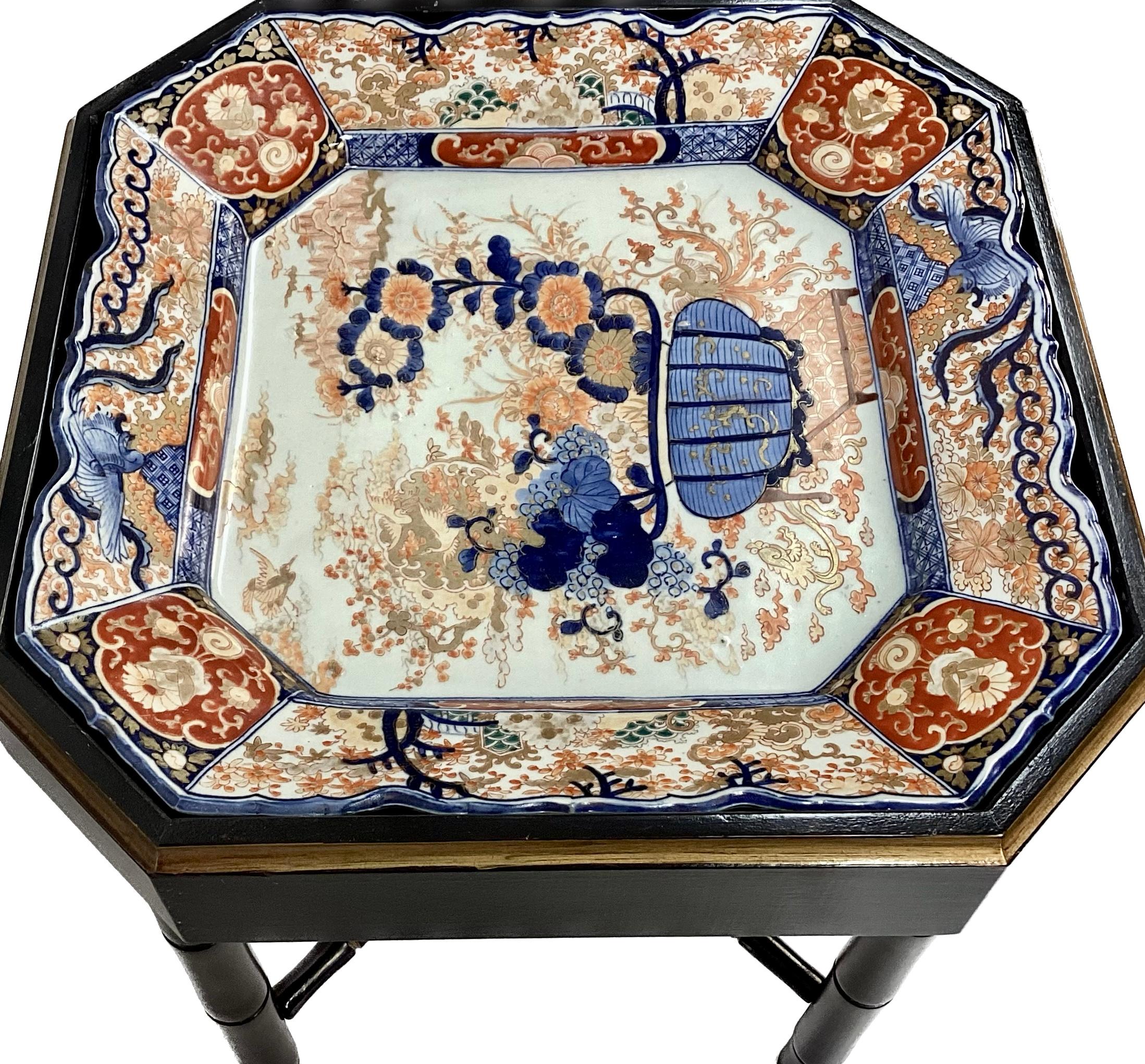 Unique vintage square faux bamboo tray table with Japanese Imari porcelain tray insert. Table is brown with gold painted trim. Tray is in multi colors of red, blue and white florals.
 