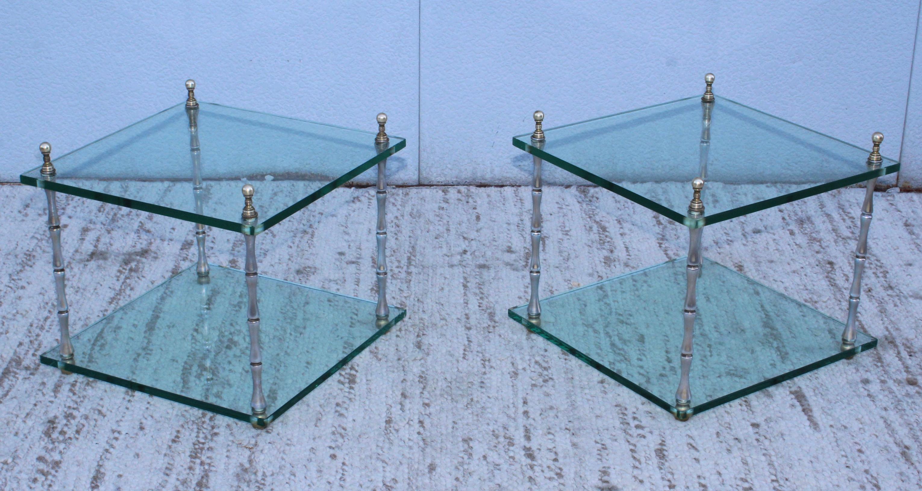 1970s Mid-Century Modern polished nickel with brass hardware faux bamboo two tier end tables by Baker, with vintage original glass. Minor wear and patina to the nickel and brass a few chips to the glass.