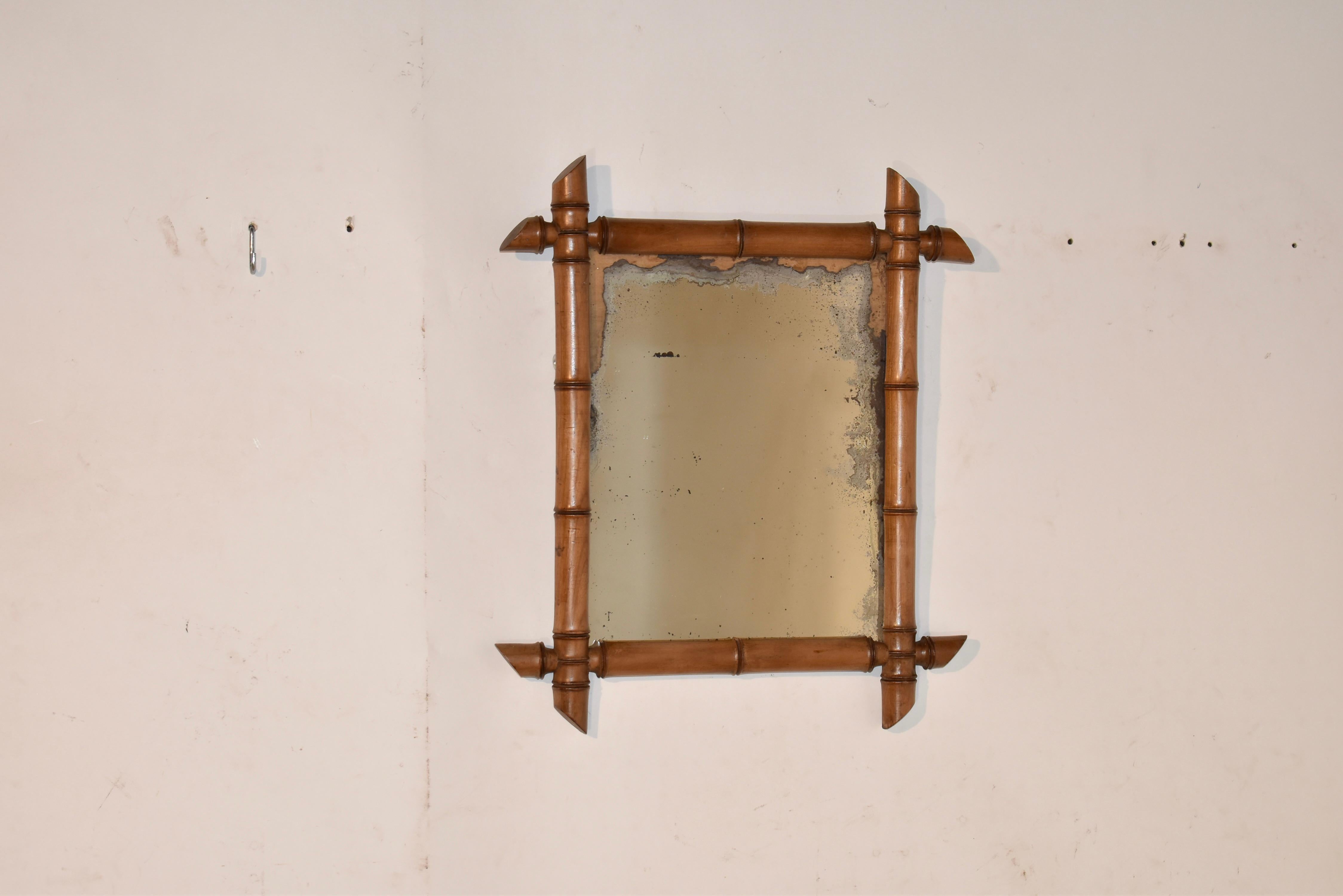 Miroir mural français en faux bambou.  le cadre du miroir est tourné à la main pour avoir l'apparence d'un faux bambou, et il entoure ce qui semble être le miroir d'origine, qui a perdu une grande partie de sa finition au mercure.  Ce miroir a