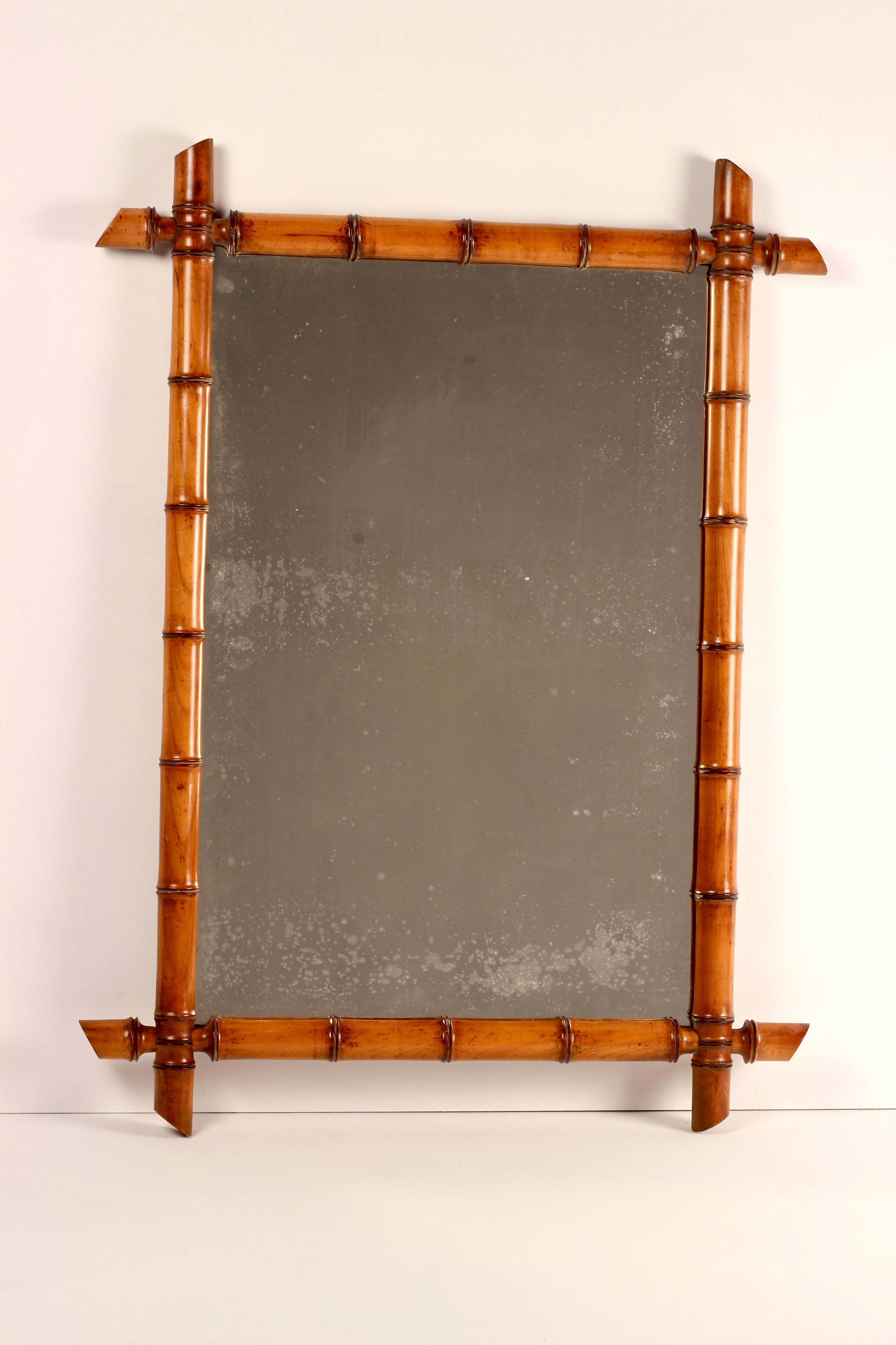 A Large faux bamboo walnut mirror of beautiful warm tones, together with its original hanging chain in the Chinoiserie/Aesthetic Movement style. The mirror reflects the age of the piece with some foxing, which we believe adds to the decorative