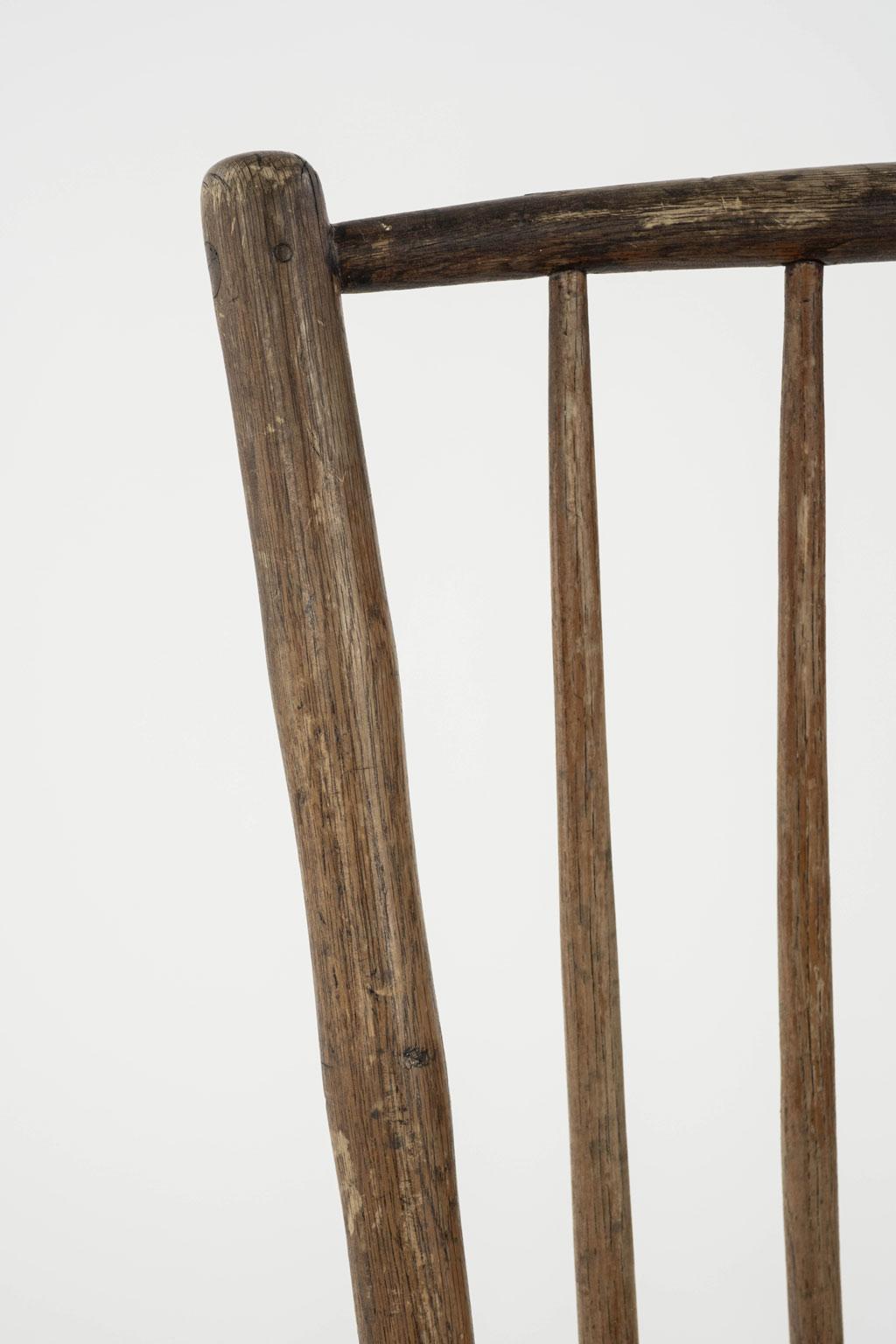 Silla auxiliar Windsor de bambú sintético con respaldo de varilla cuadrada. Montantes de imitación de bambú tallados y torneados, patas ensanchadas y camillas de fresno. Asiento perfilado de olmo. Restos de pintura marrón oscura. Data de mediados