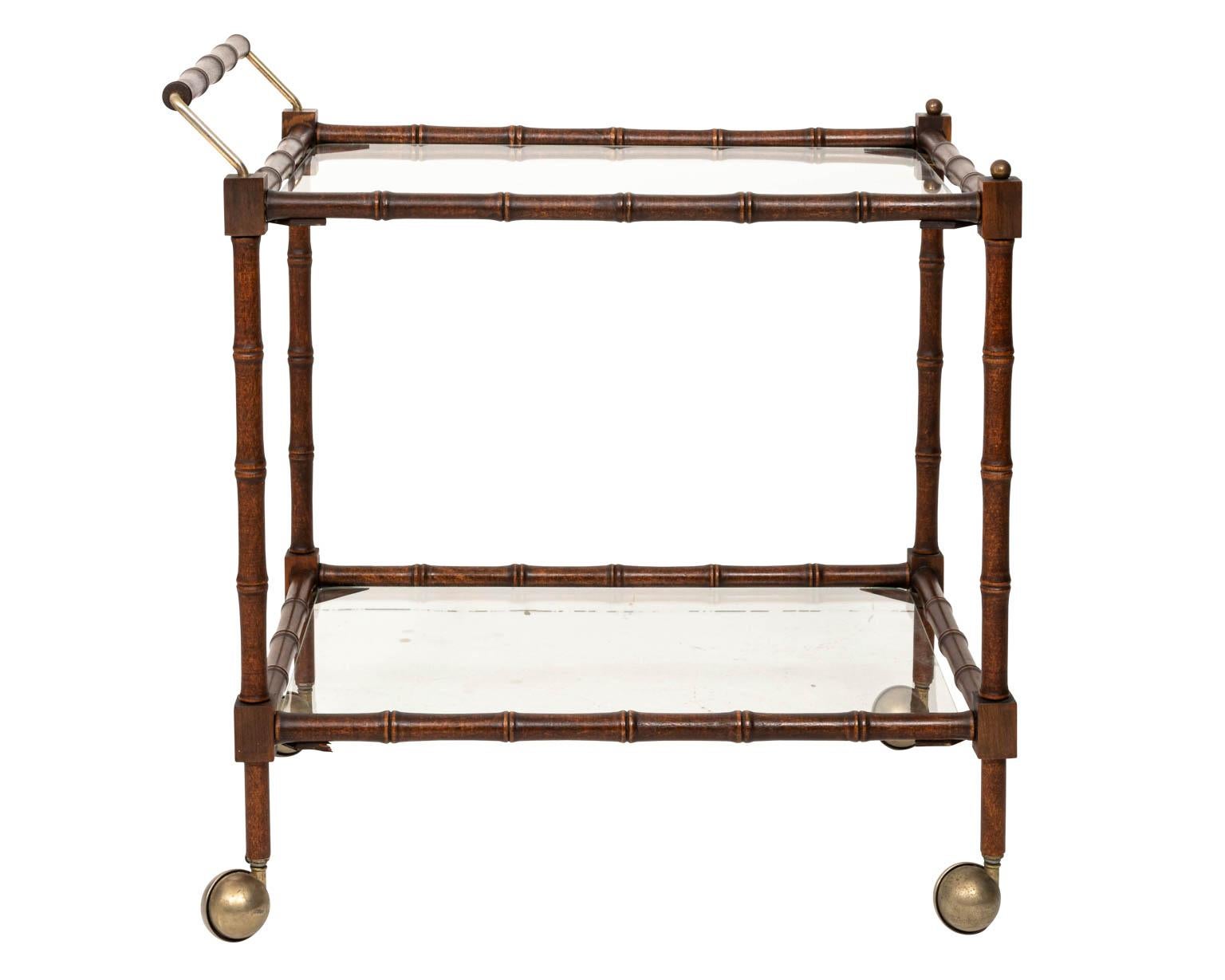 Faux bamboo bar cart, constructed of wood with two glass shelves. Good overall condition with few scratches to glass shelves. Sturdy and ready to use.