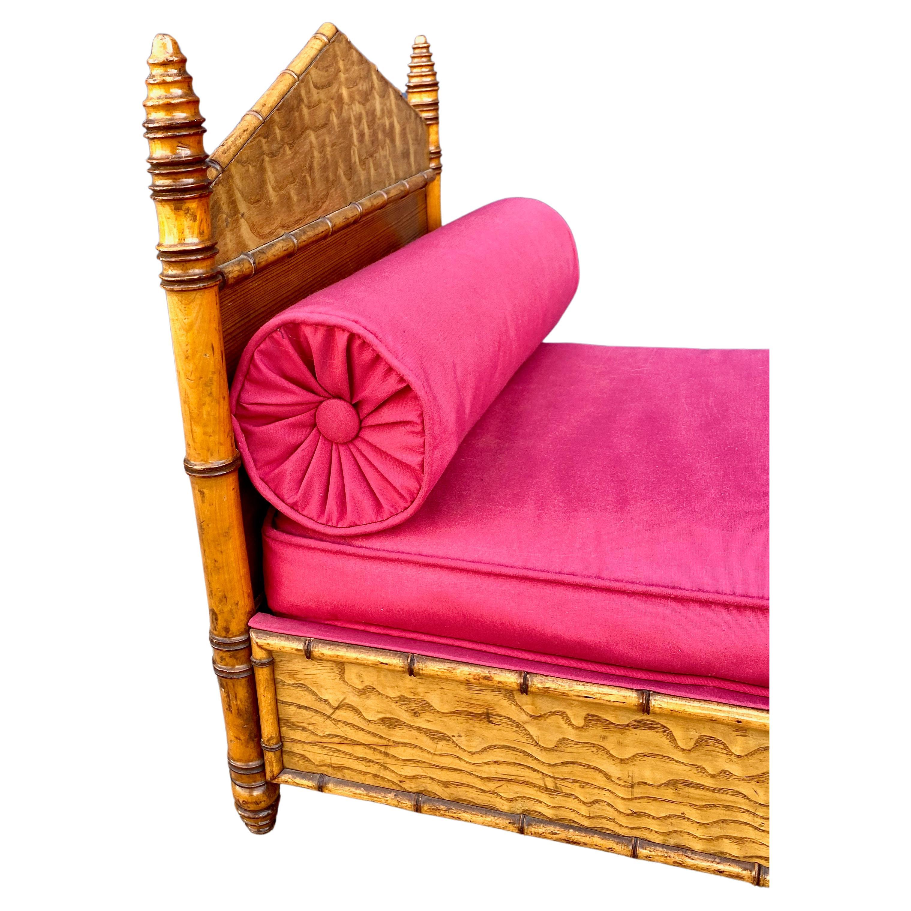 This a charming Faux Bamboo Doll Bed ( dog bed?) that date to the late 19th century. This little bed is in very good condition and features turned beehive finials, a pyramid form headboard and footboard and it is upholstered in a hot pink. The bed