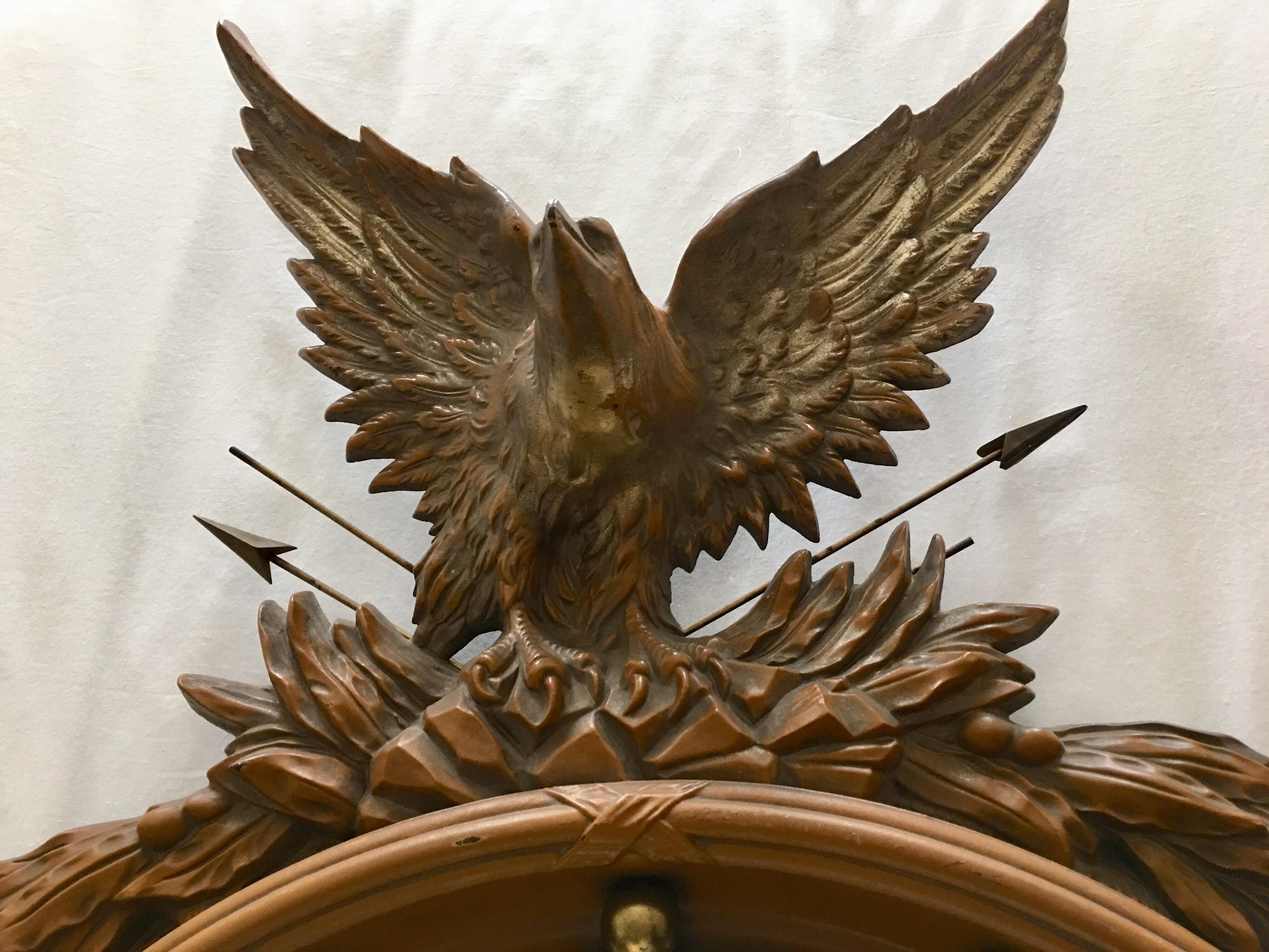 Large Mid-Century Modern sculptural Regency style convex fish eye eagle wall art mirror. The detailed carved faux wood look frame features thirteen gilded balls and a traditional crest with metal arrows and acanthus foliate garland decoration.