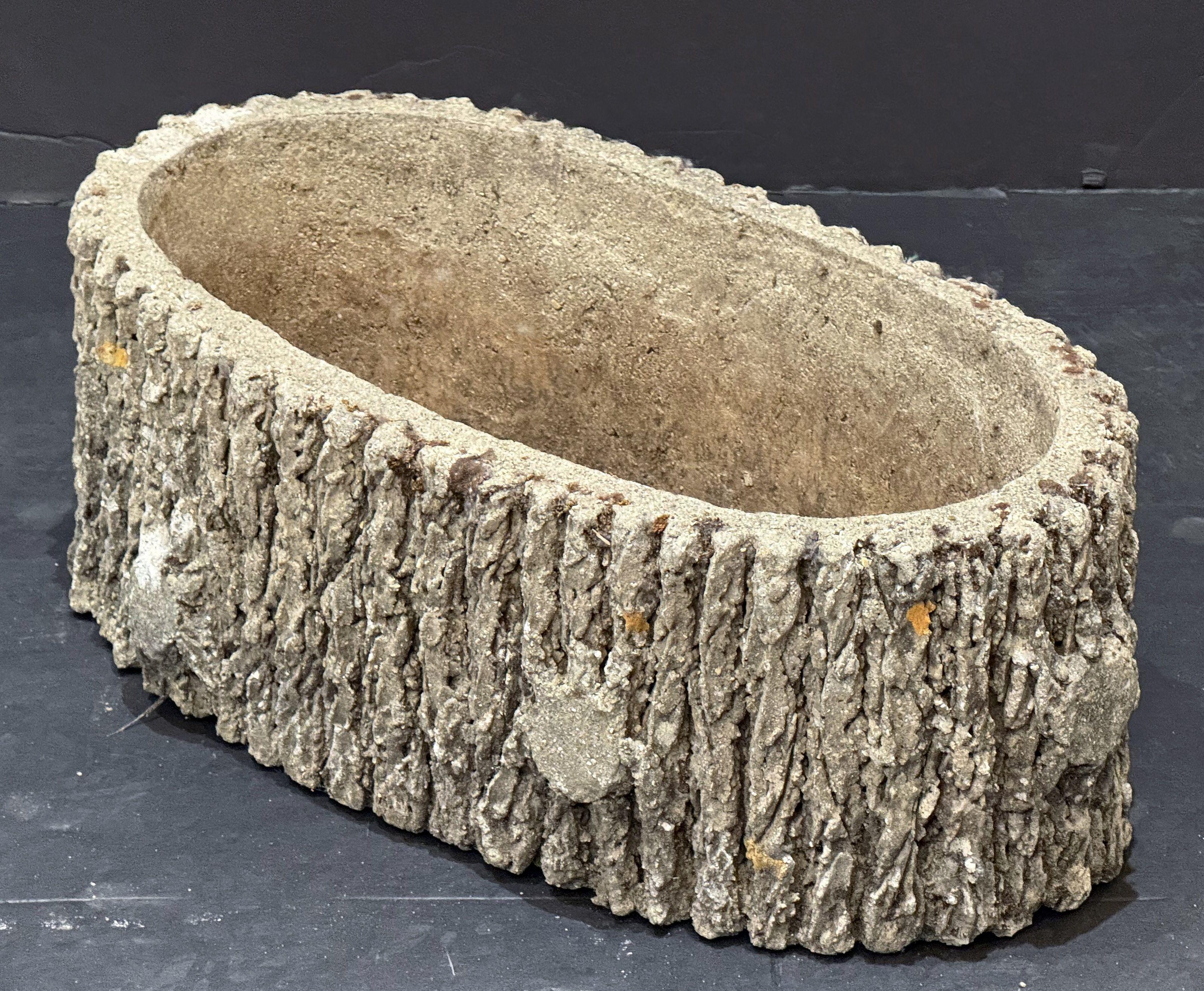 Un bel vaso ovale da giardino francese in pietra composita, con un rivestimento in finto bois o corteccia d'albero lungo la circonferenza.

 