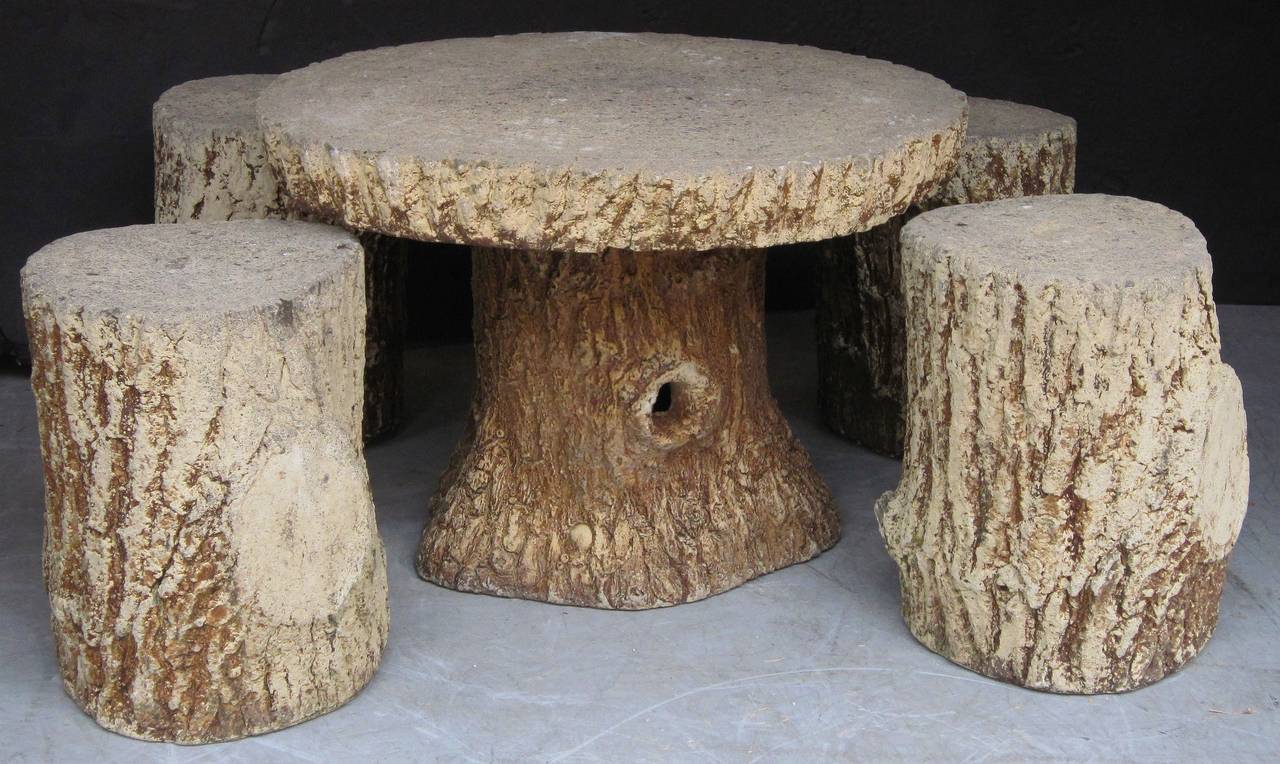 A lovely French faux bois garden stone set (includes table and four stools), each piece featuring a naturalistic relief design of a tree trunk.
Of composition stone.

Table dimensions: Approximately height 21 inches x diameter 30 inches
Each stool's