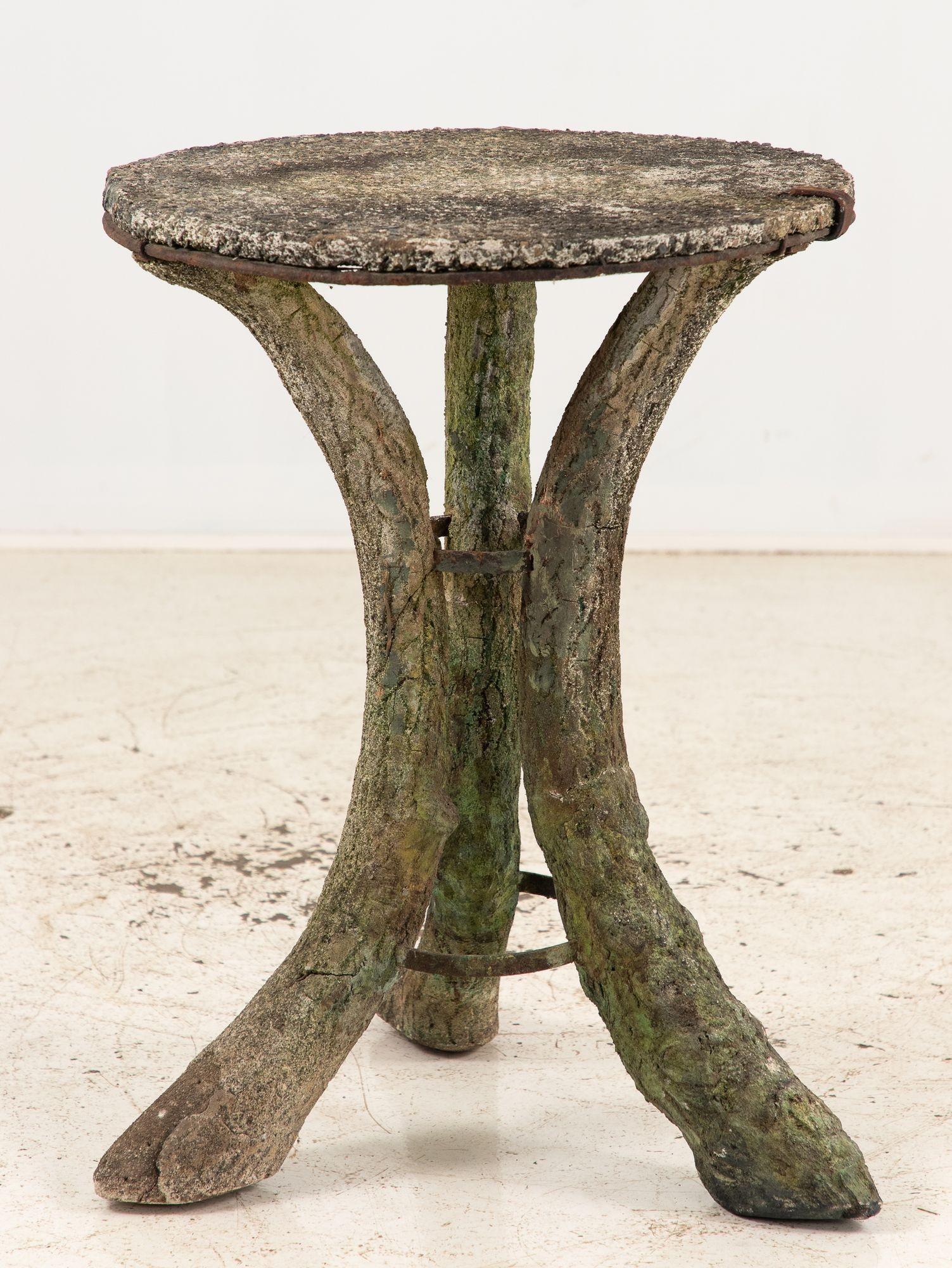 An early 20th-century faux bois table from Scotland, featuring a charmingly rustic design. The round tabletop is supported by three splayed legs, showcasing intricate wood grain details that mimic natural wood. Iron reinforcements have been added to