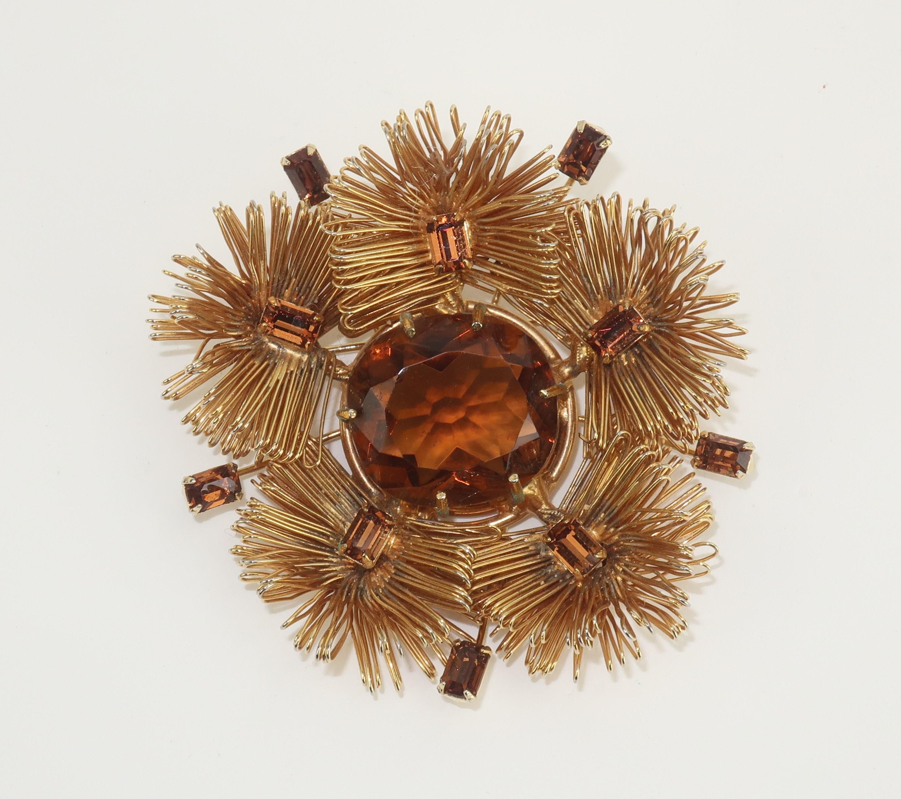Beautiful gold tone brooch embellished with brown topaz colored crystals in the form of an abstract pinecone bloom.  The intricate design utilizes looped wiring which creates a feathery look perfect for embellishing Fall and Winter lapels. 