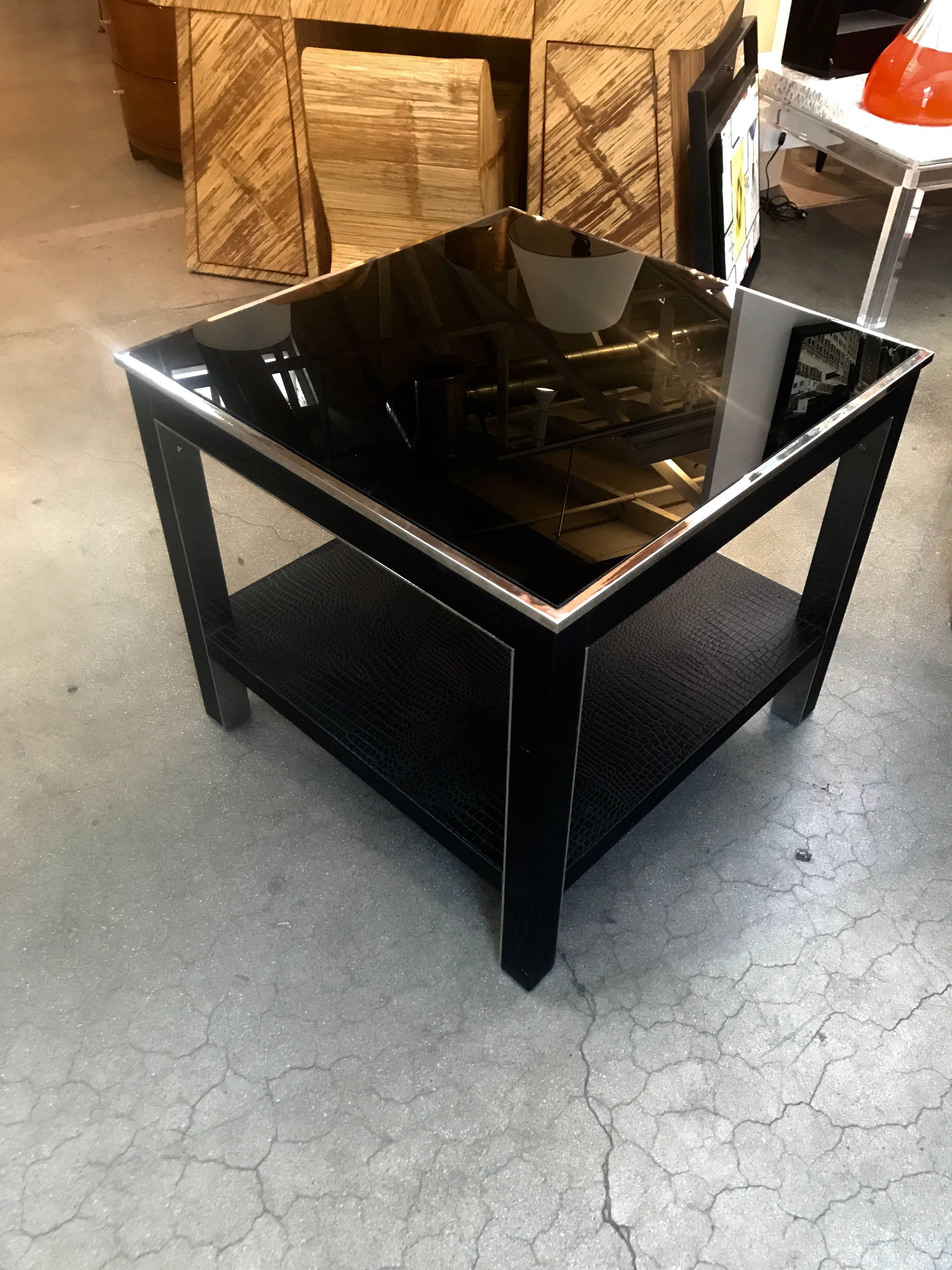 A very nice quality dark glass table with a faux crocodile leather or vinyl covering and steel insets. No labels but very high quality. The top glass piece is new. The original had cracked and we replaced it. There are some marks to the leather or