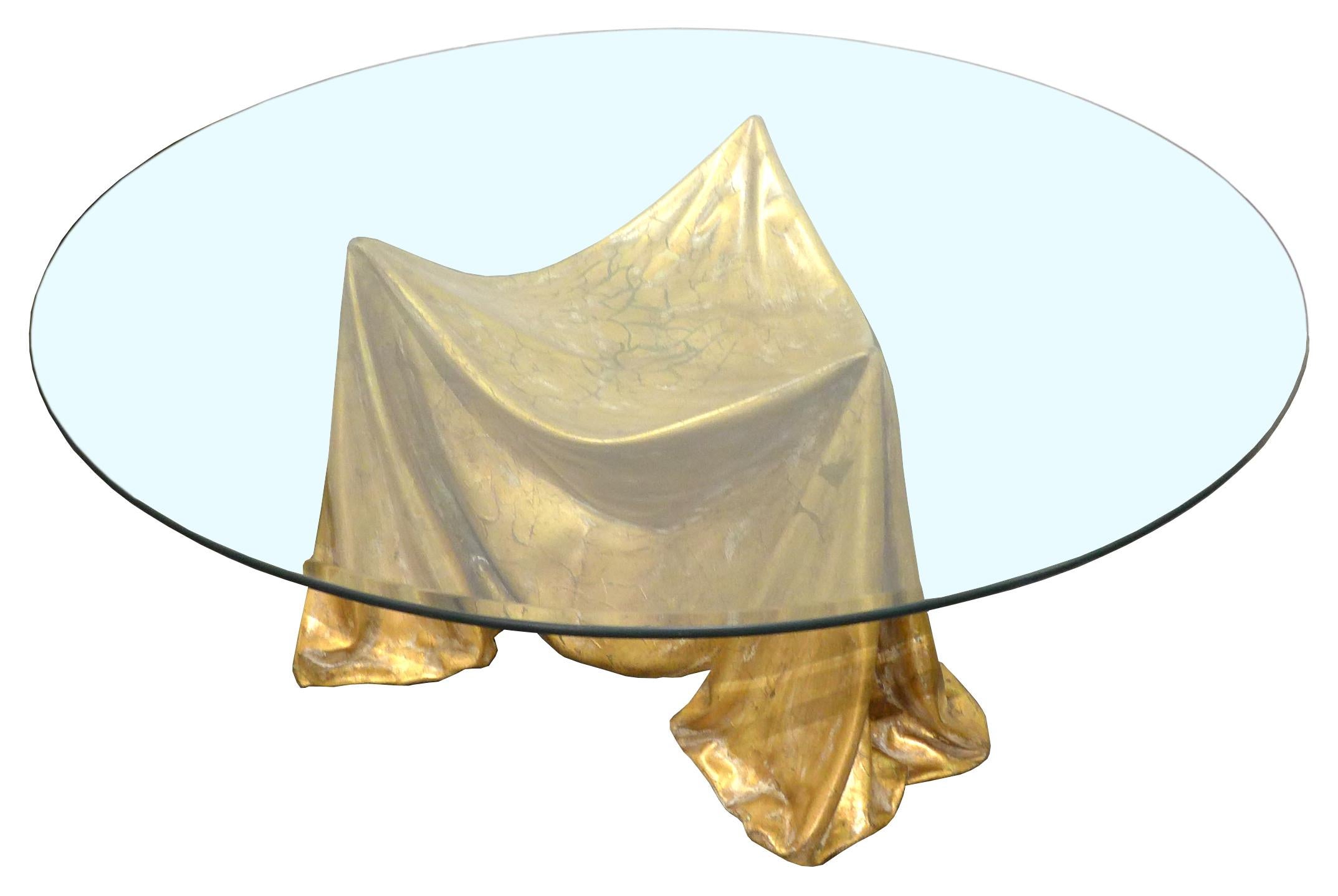 A wonderfully surrealistic, troupe l'oeil faux-fabric coffee table with a round glass top. A dramatic and alluring form made of gilt and reinforced plaster. An exceptional example of fantasy furniture with an extremely strong decorative presence