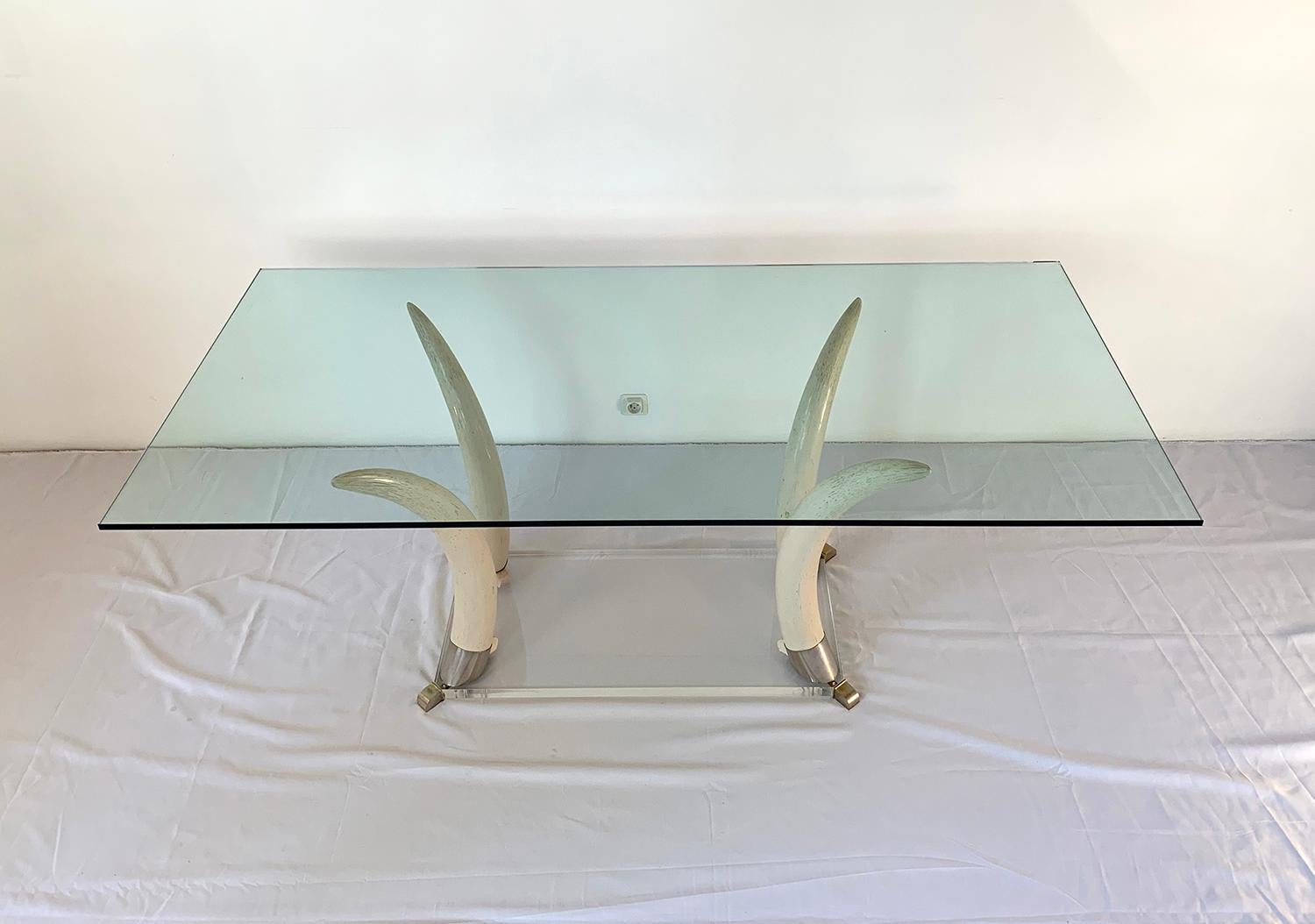 Magnificent dining table, 1970s. The base is made up of four elephant tusks made of resin joined by a Lucite base and surmounted by a glass tray.

Magnifique table de salle à manger, 1970s. Le pied est composé de quatre défenses d'éléphant en