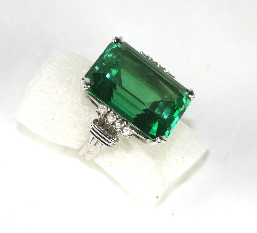 Attractive Faux Green Tourmaline Cocktail Ring from the 1970's with large emerald cut stone and faux diamond accents. A high quality synthetic set in 14k white gold. 
Tiny size, 4 USA. Signed 