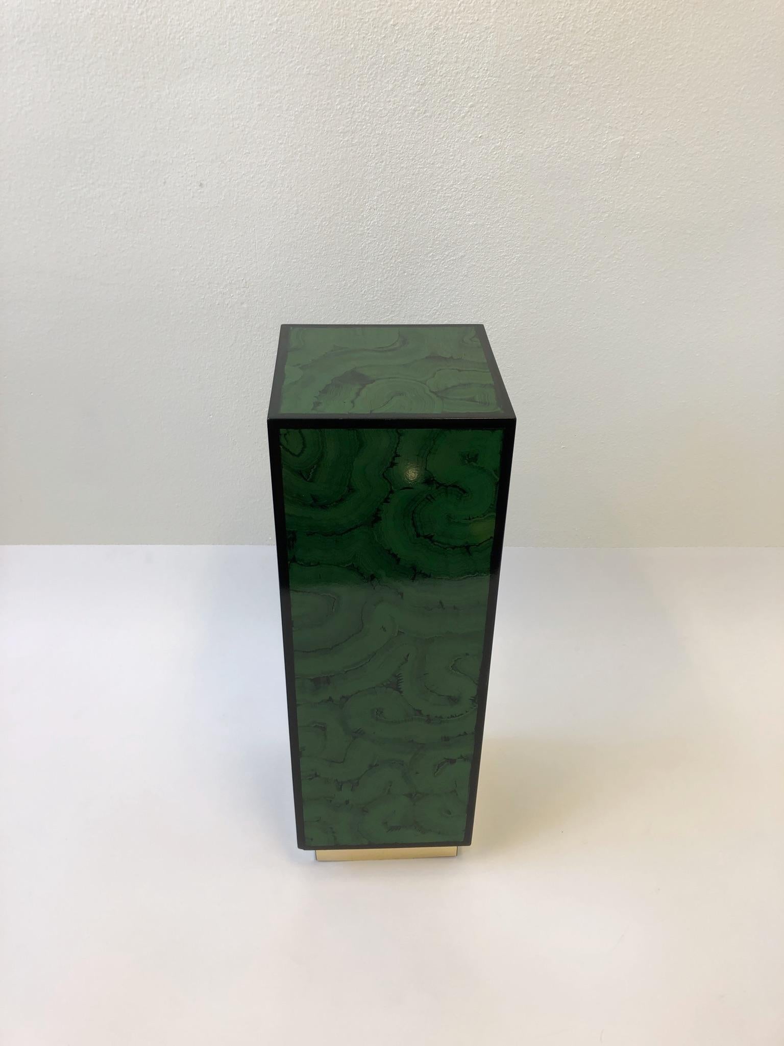A glamorous 1970s faux malachite lacquer and brass modern pedestal. The pedestal is constructed of wood that’s lacquered in a malachite pattern and outlined black with a brass veneer base.
Dimensions: 12” deep, 12” wide, 36” high.