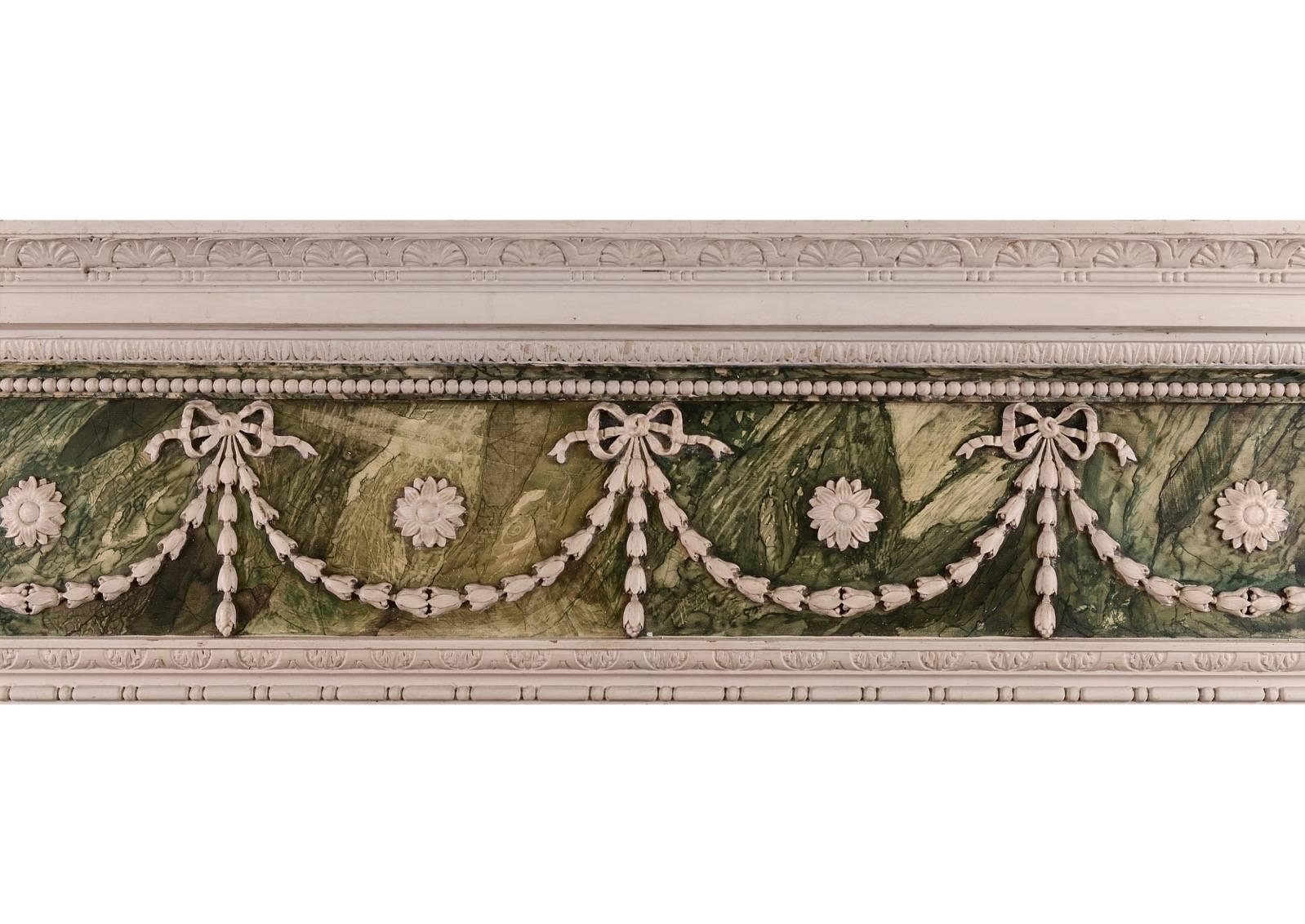 Un camino dipinto, in finto marmo, legno e gesso in stile Adam. Gli stipiti con drappeggi a cascata, sormontati da urne neoclassiche. Il fregio è caratterizzato da fasce a campana, nastri legati e patere. Il ripiano del fronte di rottura con