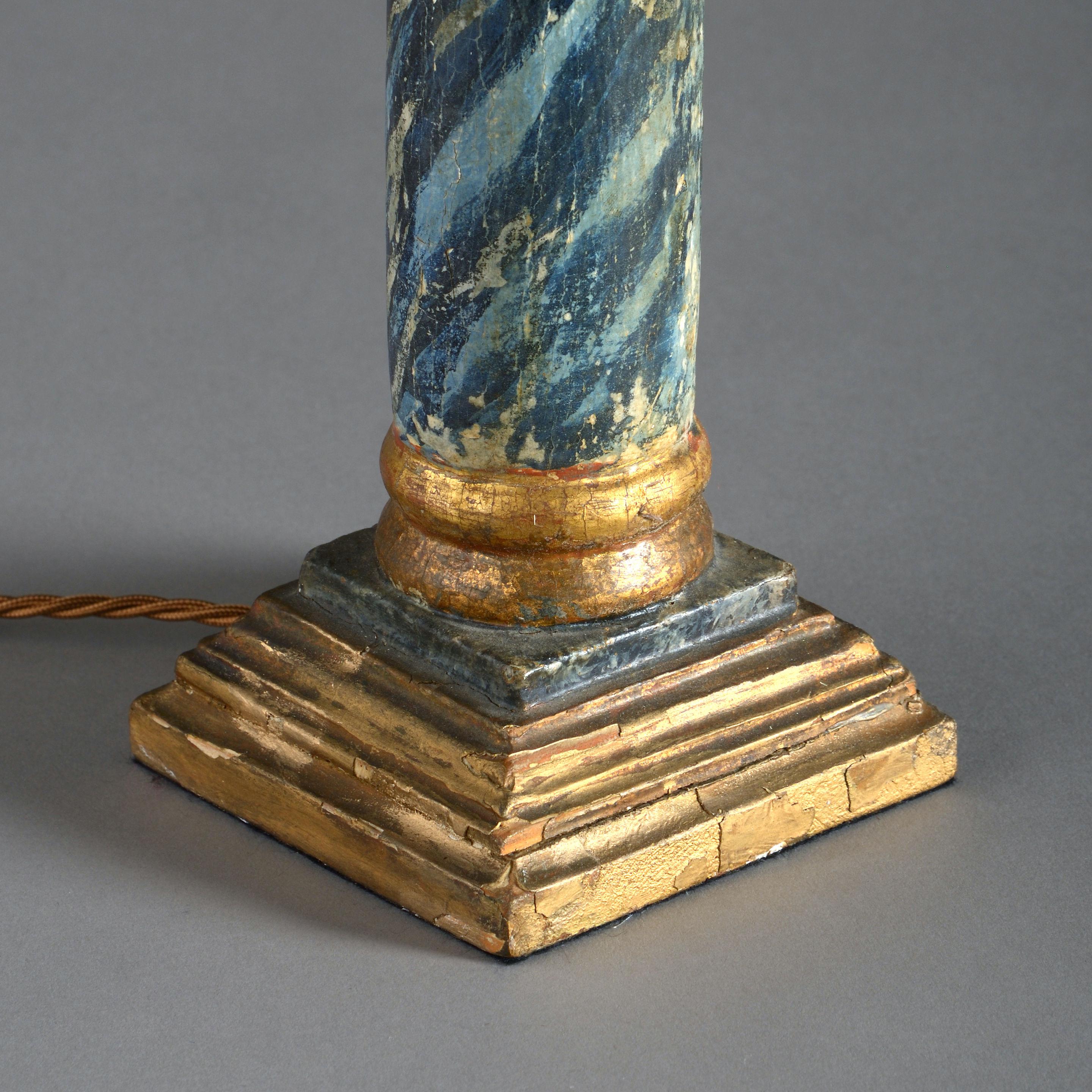 An early 18th century column, having a gilded composite Corinthian capital above a faux painted marble stem and set upon a stepped giltwood plinth base. 

Now wired as a table lamp base.