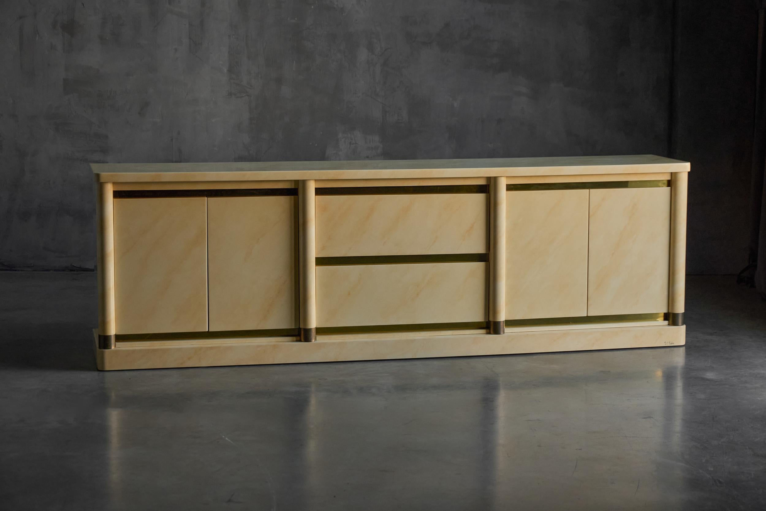 This refined French cabinet by Jean-Claude Mahey showcases his signature faux–marble lacquered finish in warm cream tones, creating an elegant stone-like appearance with a luxurious sheen. The long, structured façade is defined by vertical column