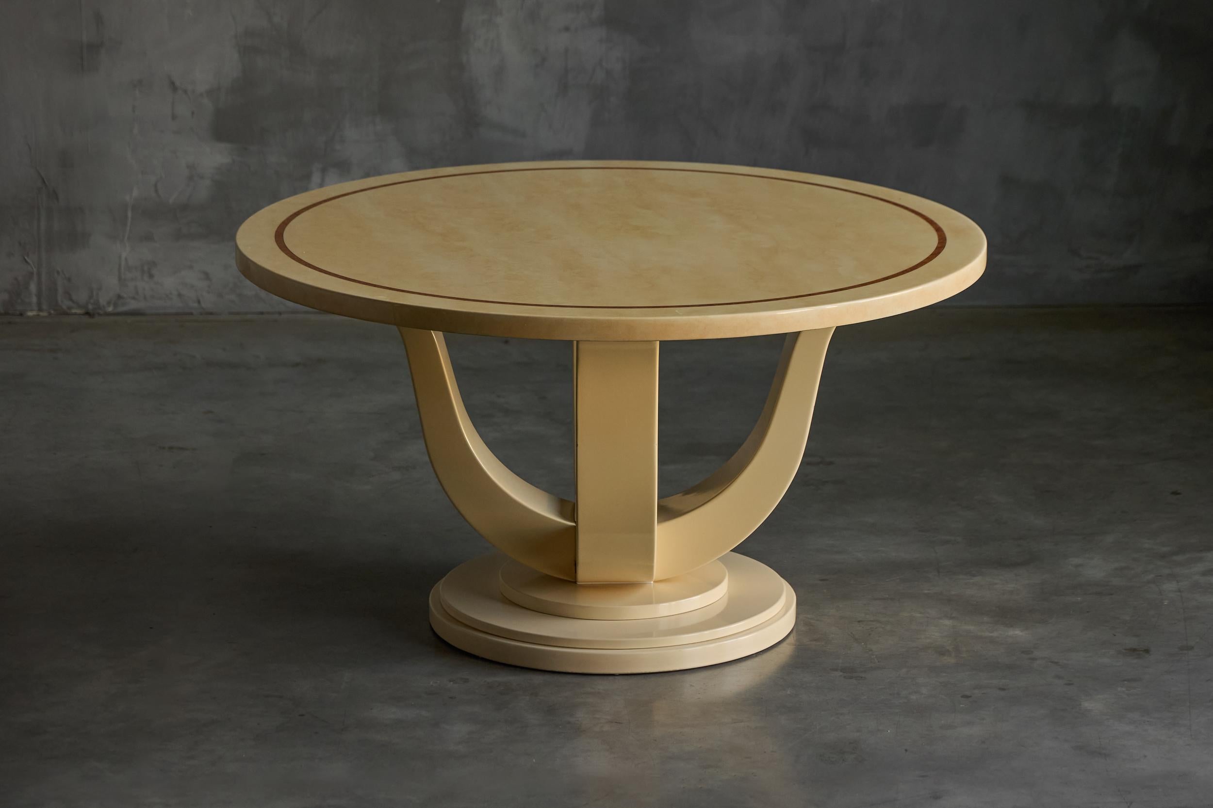 Esta llamativa mesa francesa redonda de Jean Claude Mahey tiene un tablero lacado de imitación mármol de alto brillo en cálidos tonos crema, realzado por un motivo circular incrustado en contraste. Su escultural base de pedestal, compuesta por tres