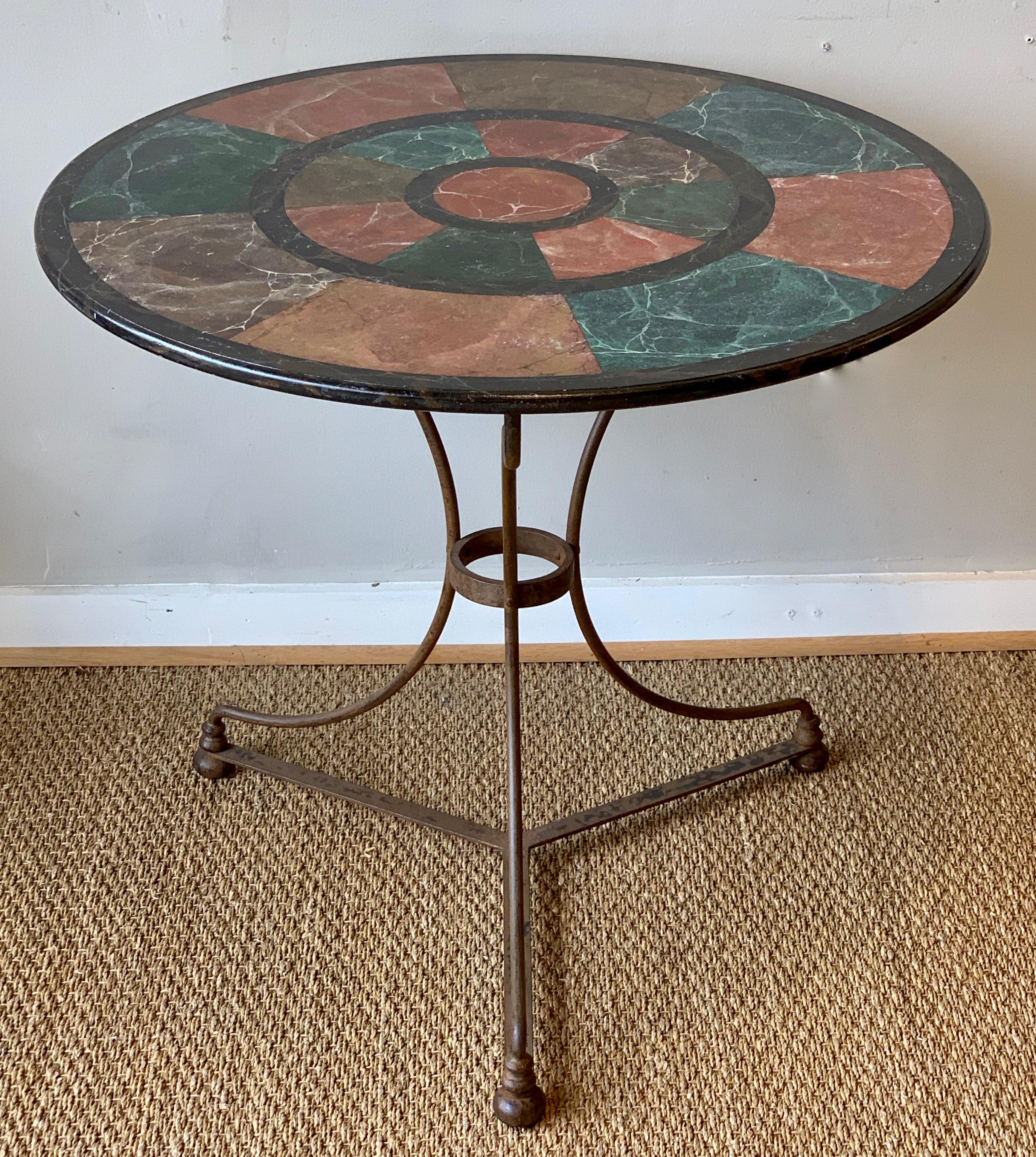 A beautifully painted faux marble-top table resting on an iron three-legged pedestal dating from the 1960s.