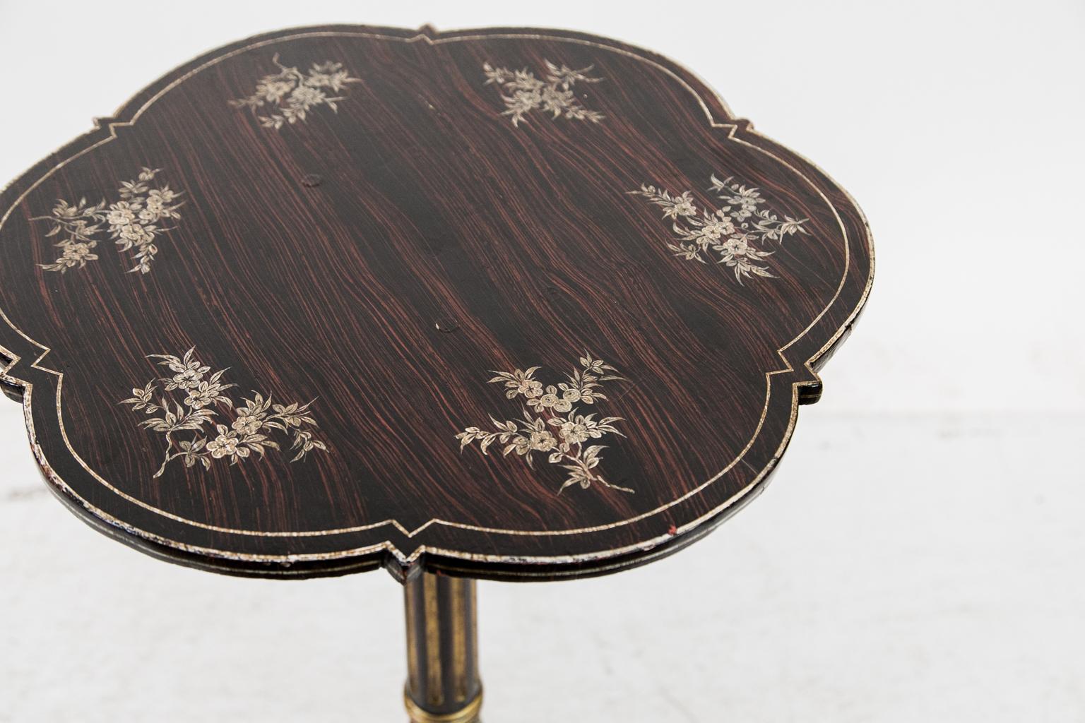This tripod table is faux painted to simulate wood grain all over. The top is painted with floral sprays and simulated double line inlay on the border. The upper stem is fluted and highlighted with gold. The lower stem has a shallow knop carved with