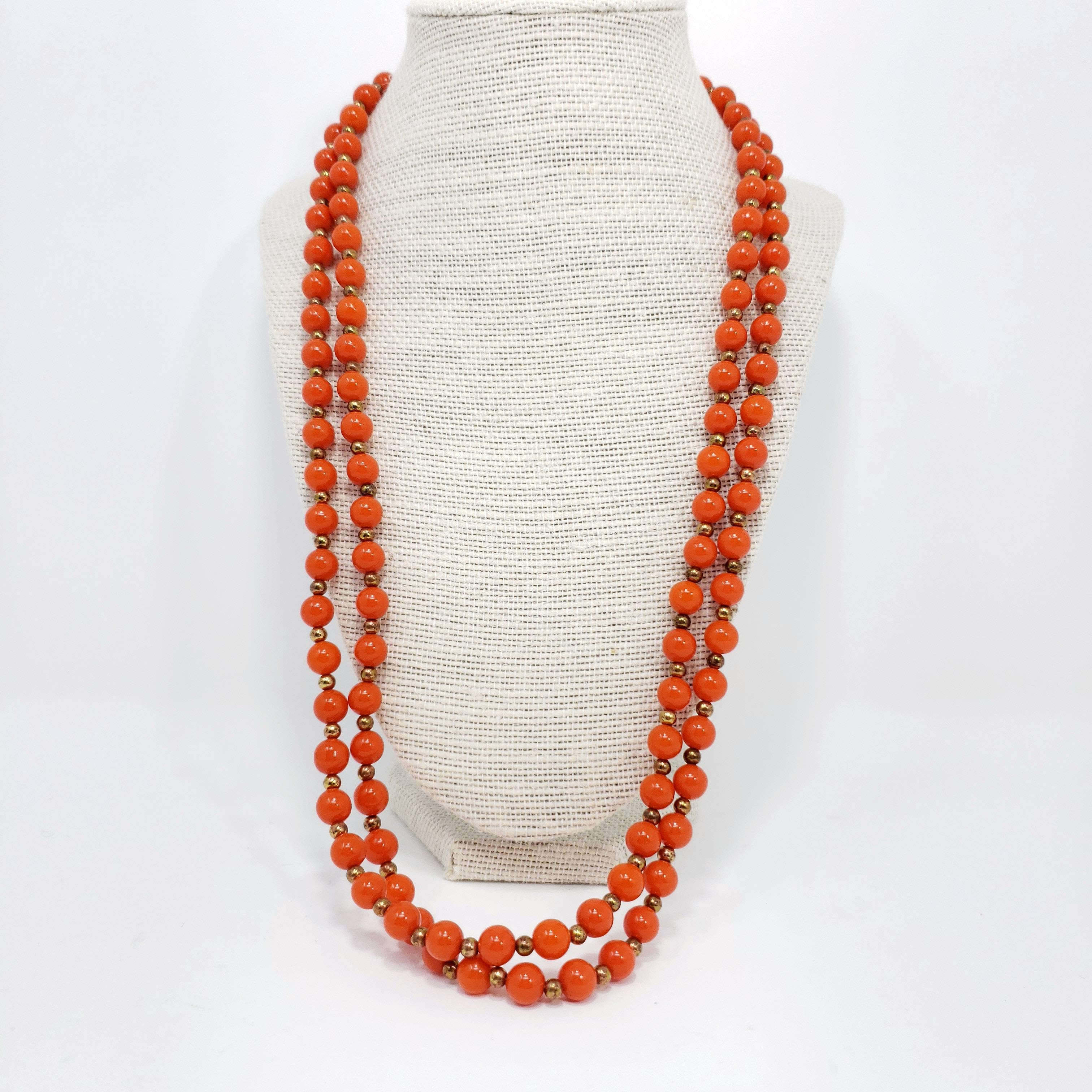 Matching vintage faux salmon coral bead necklace and earrings, accented with glowing gold-tone beads and motifs.

Circa mid 1900s.

Necklace: 52 inches around
Earrings: 1.25 inches x 0.8 inches