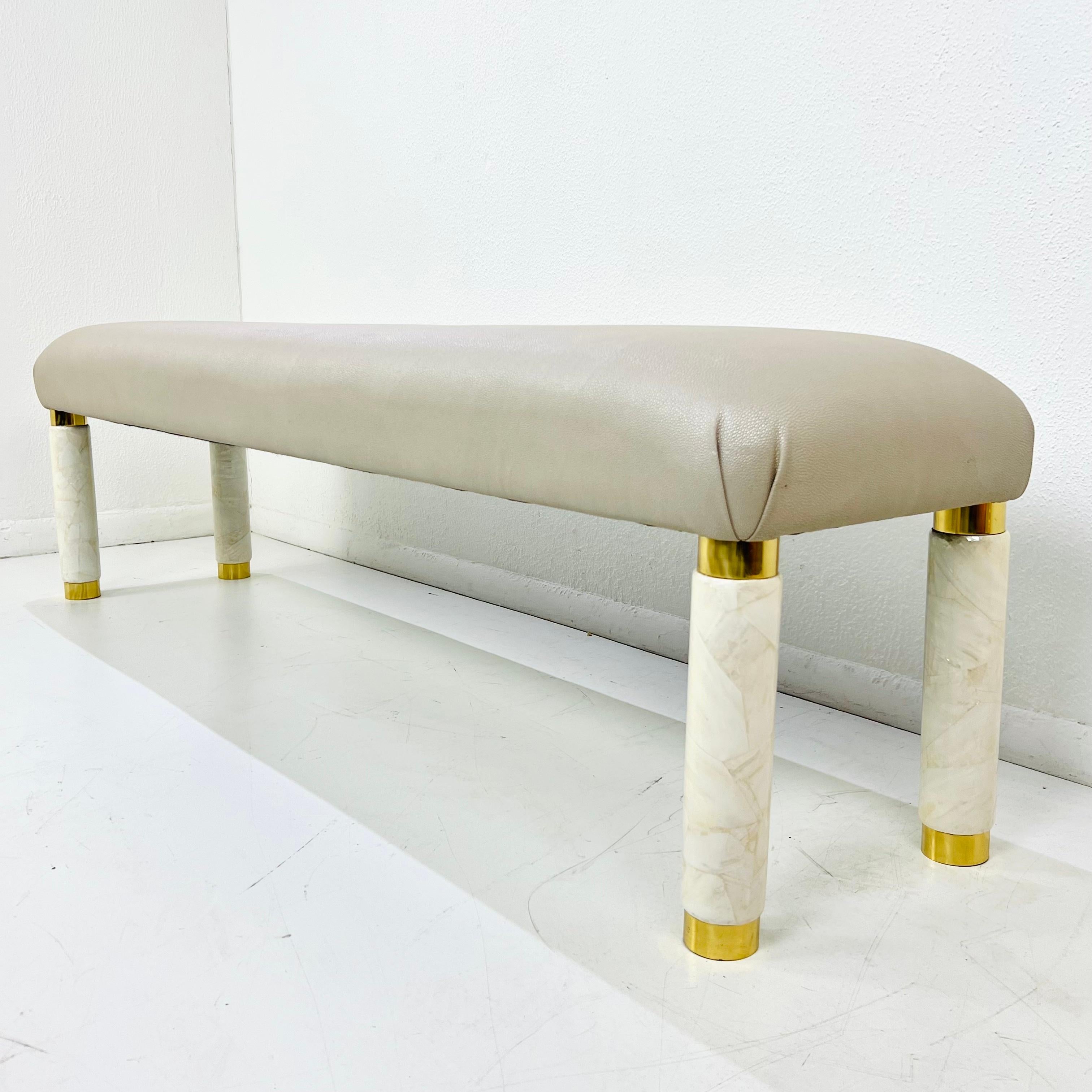 Questa panca vintage dalle linee pulite e dalla personalità lussuosa abbina una seduta in finto zigrino color taupe a gambe cilindriche scultoree in finta pietra/composito color crema. Le morbide venature delle gambe si abbinano magnificamente al