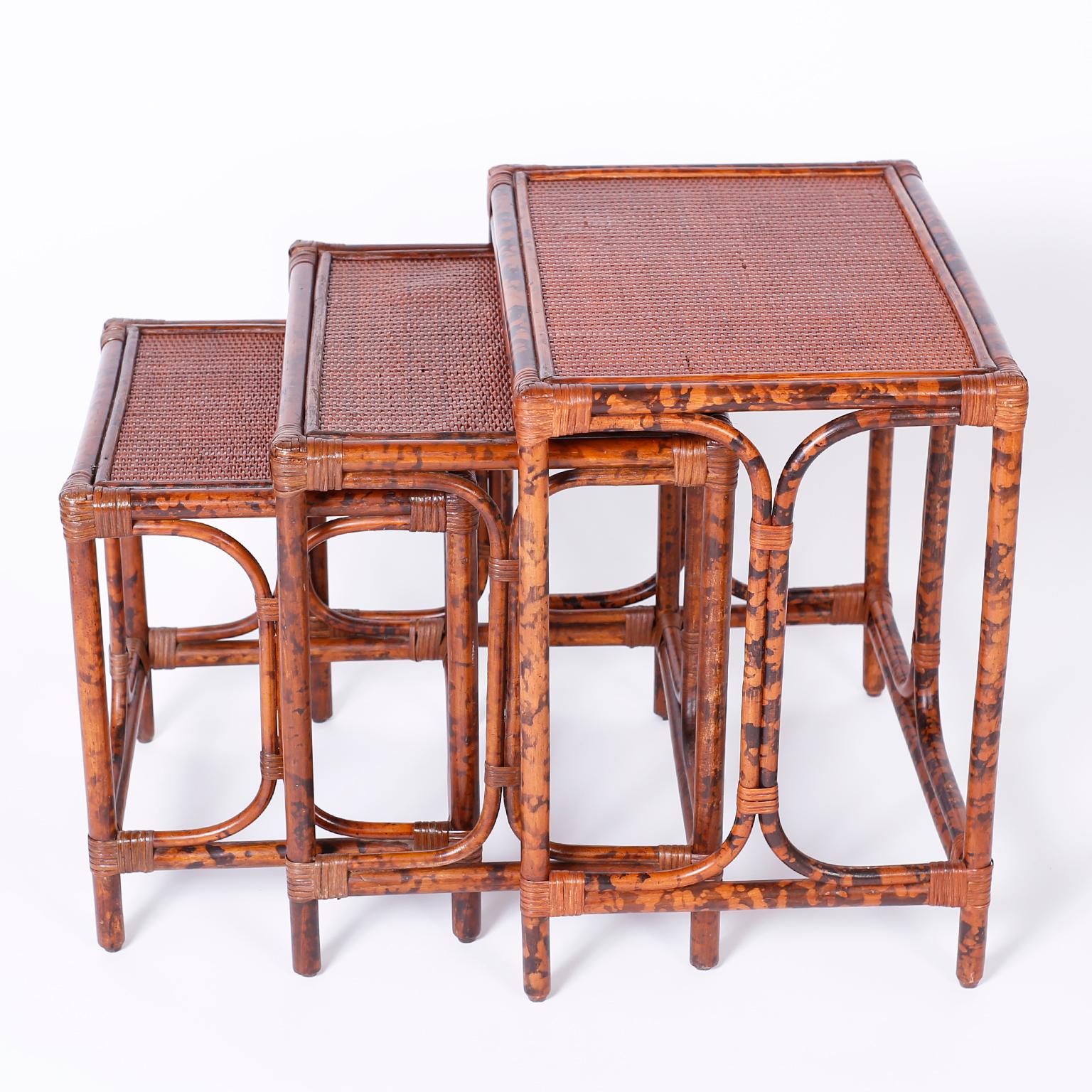 Nest of three tables with faux tortoise wood and bent wood faux bamboo frames wrapped with reed at the joints and grass cloth tops on all three.

Measures: Largest to smallest:

H 22 W 20 D 18
H 21 W 19 D 16
H 16 W 14 D 13.