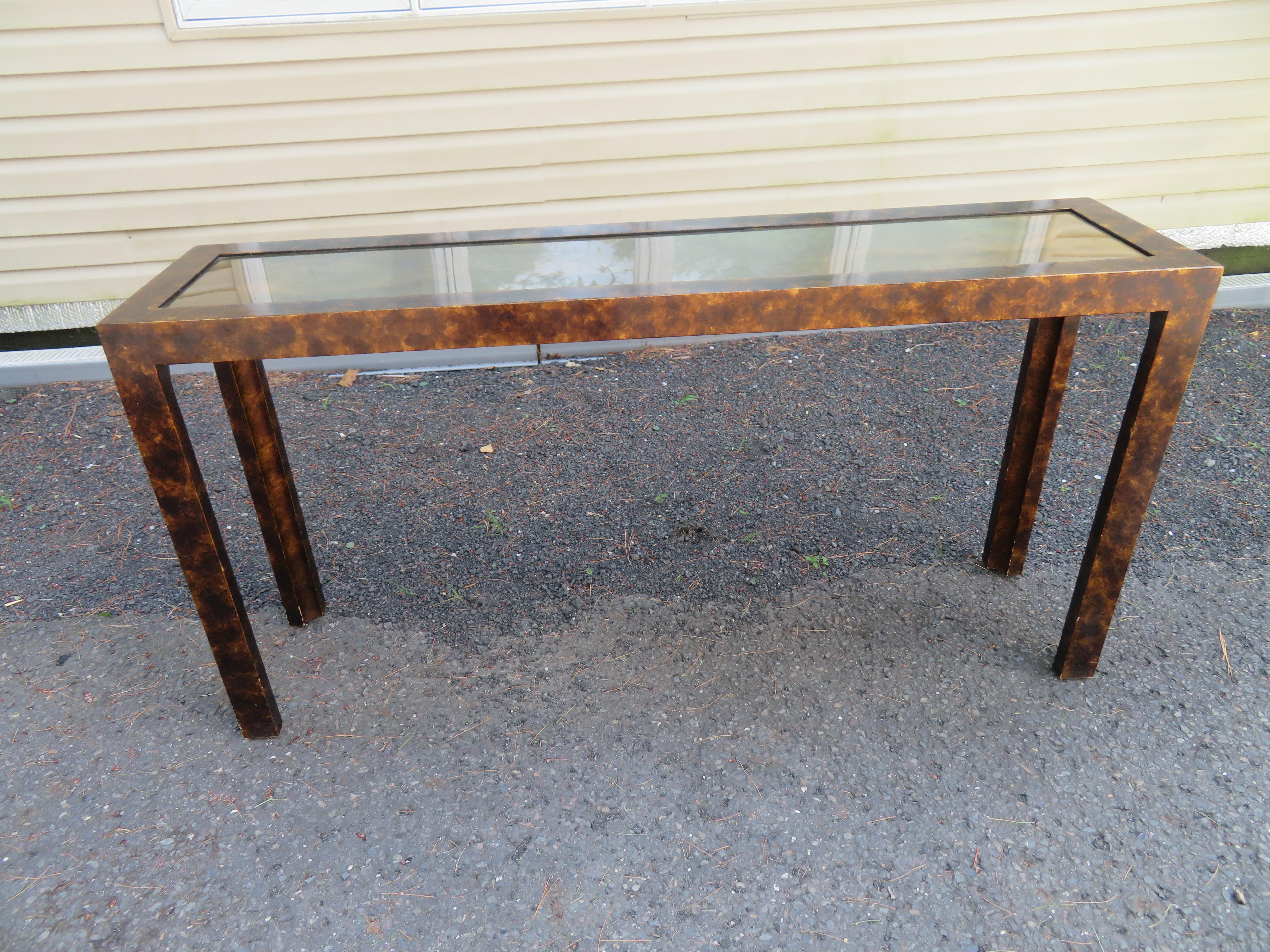 Handsome Parsons-style faux tortoise shell finish console table with a patinated brass-clad top. This piece measures: 28.5