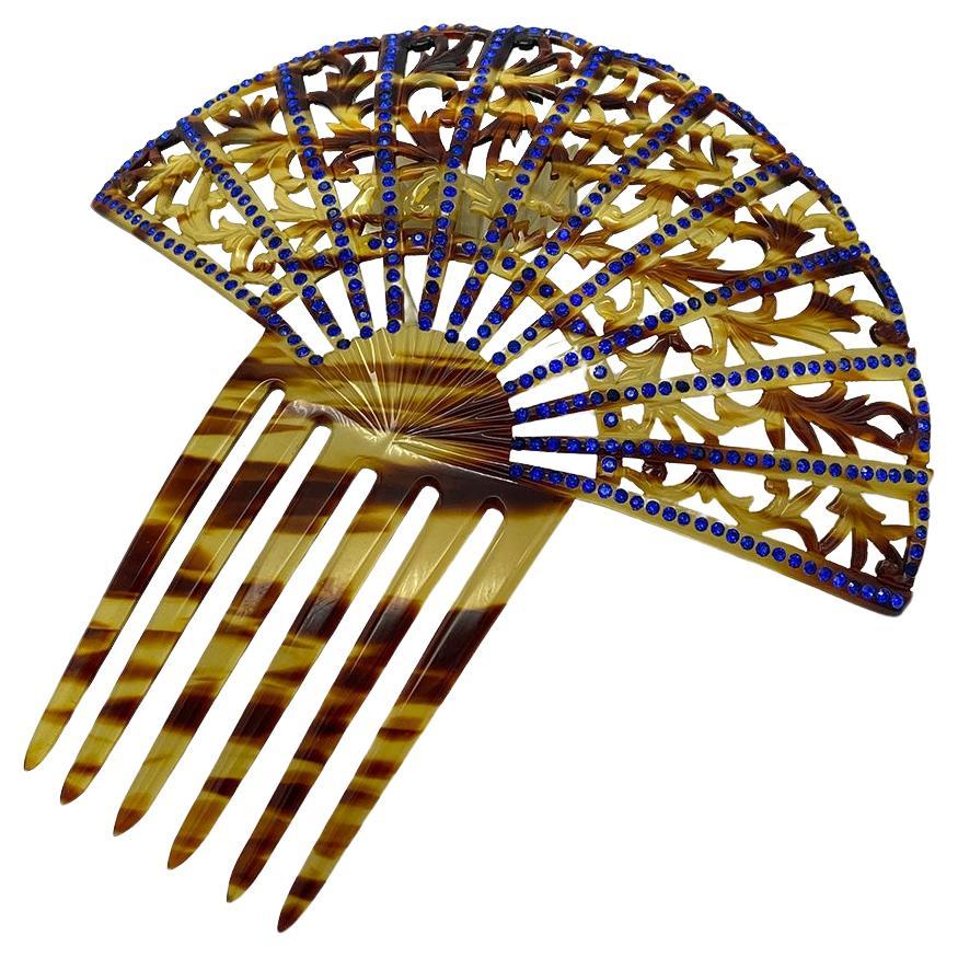 Si tratta di una peineta in finto guscio di tartaruga con sei forchette. Questo ornamento per capelli, un grande pettine decorativo a forma di ventaglio, presenta piccoli strass blu. Le donne del mondo ispanico sono solite indossarli sotto una