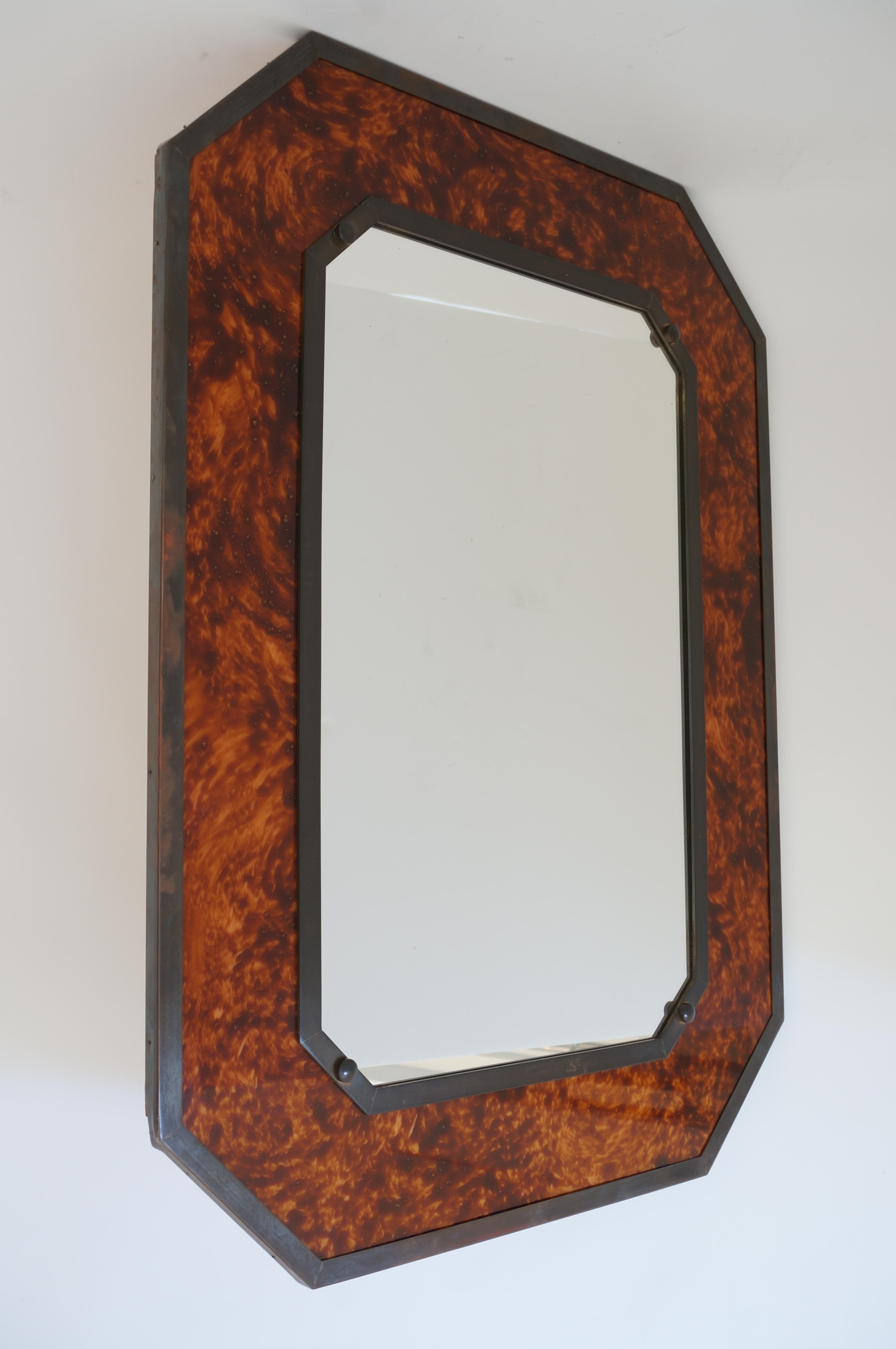 This stylish and chic wall mirror dates to the 1970s and is fabricated in patinated bronze with faux (lucite) tortoiseshell panels.